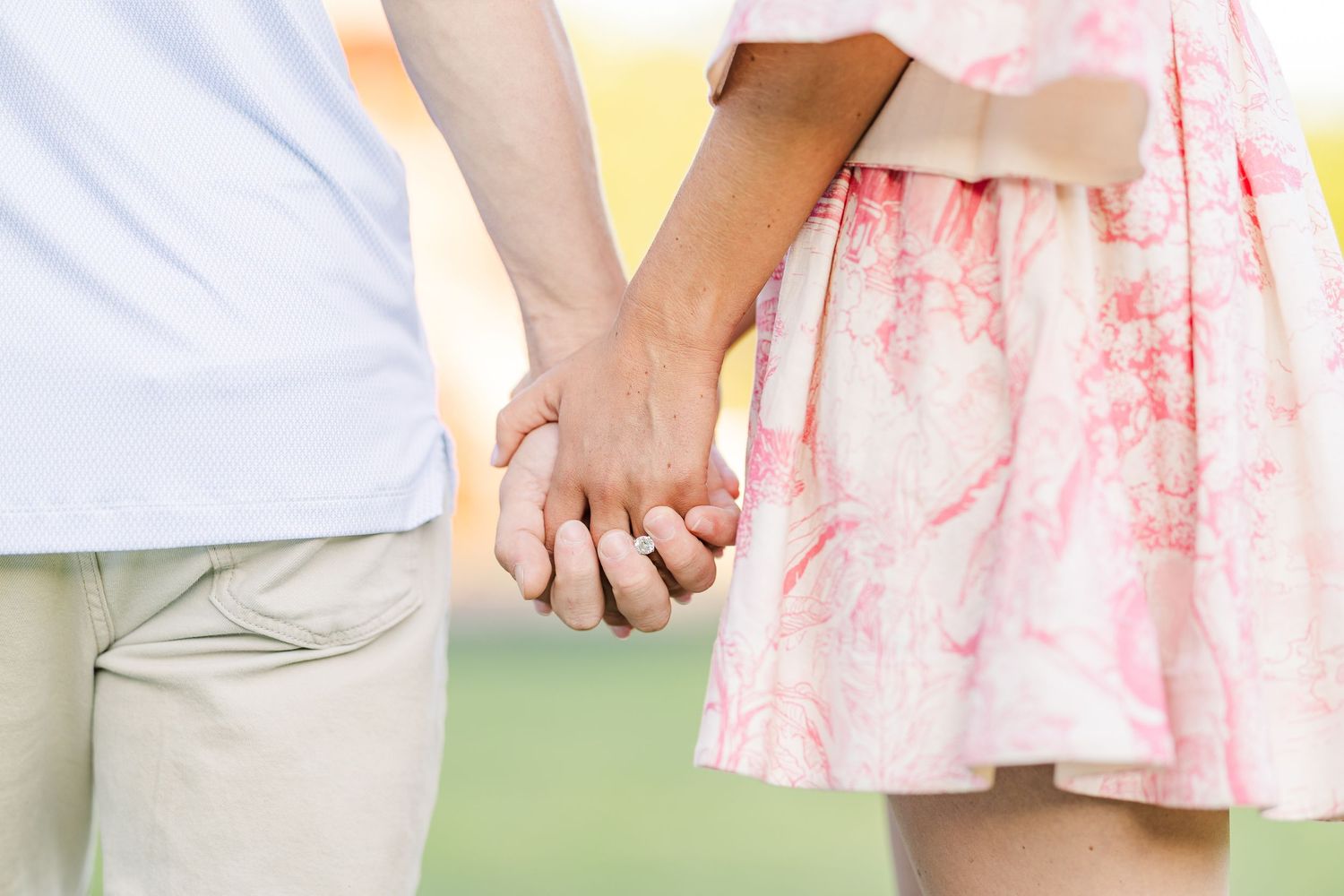 Close-up shot of a couple holding hands while wearing summer attire.