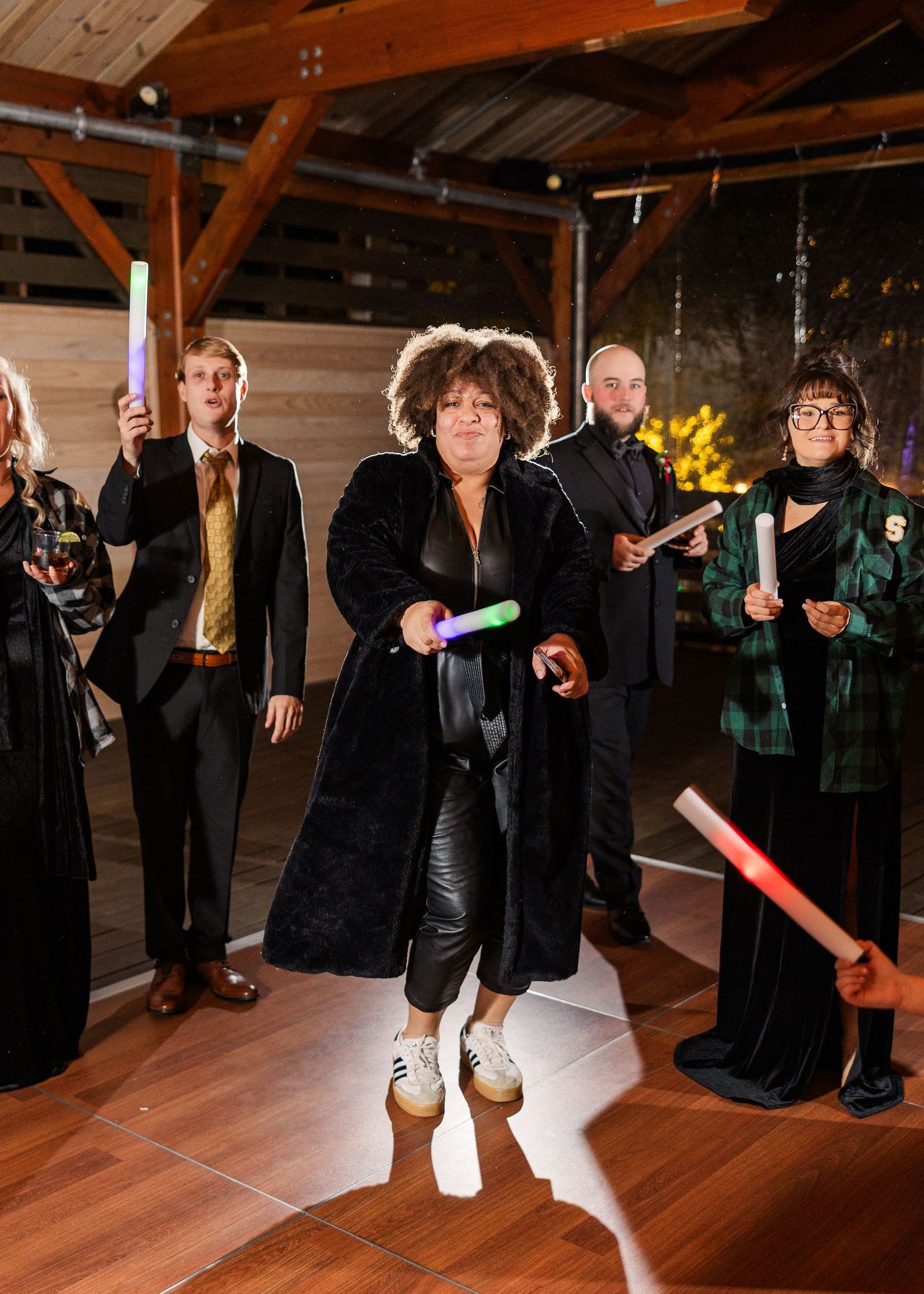 Wedding guests holding light sabers on a wooden dance floor during evening reception wedding groom bride wilmington North Carolina photograp