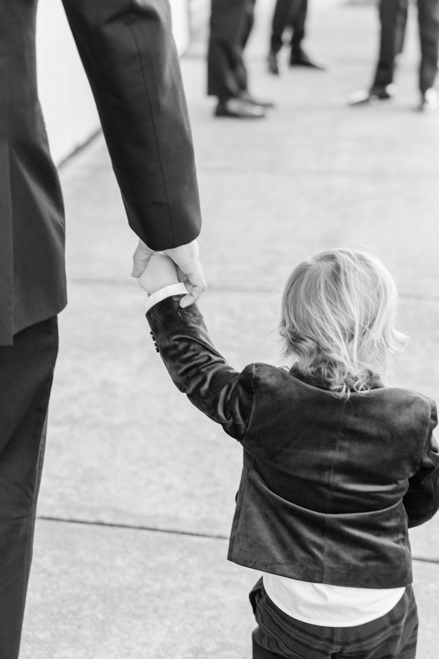 Low angle shot of small child in formal wear reaching up to adults at wedding wedding groom bride wilmington North Carolina photographer