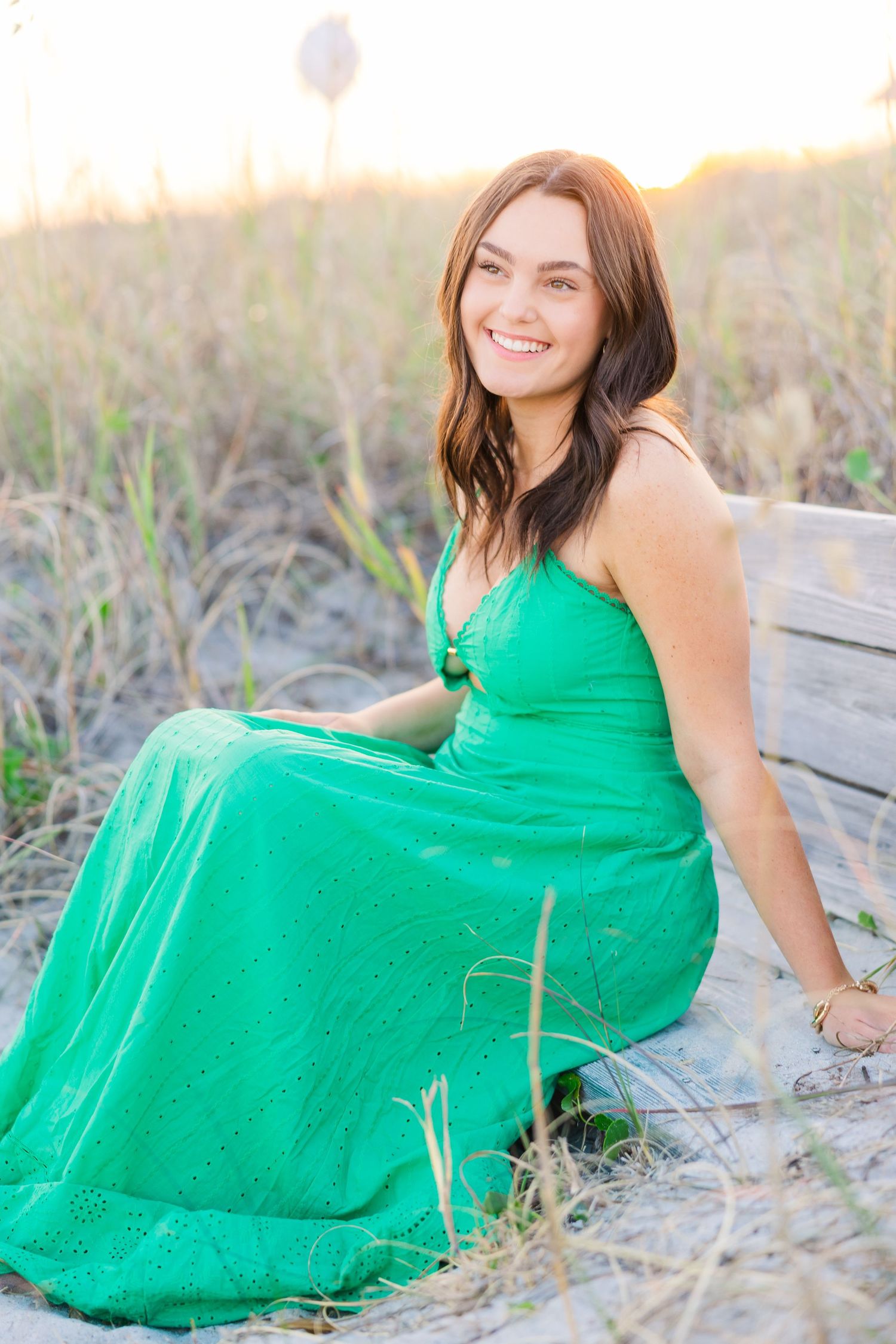Relaxed beach portraits featuring a kelly green dress against sandy dunes at golden hour.