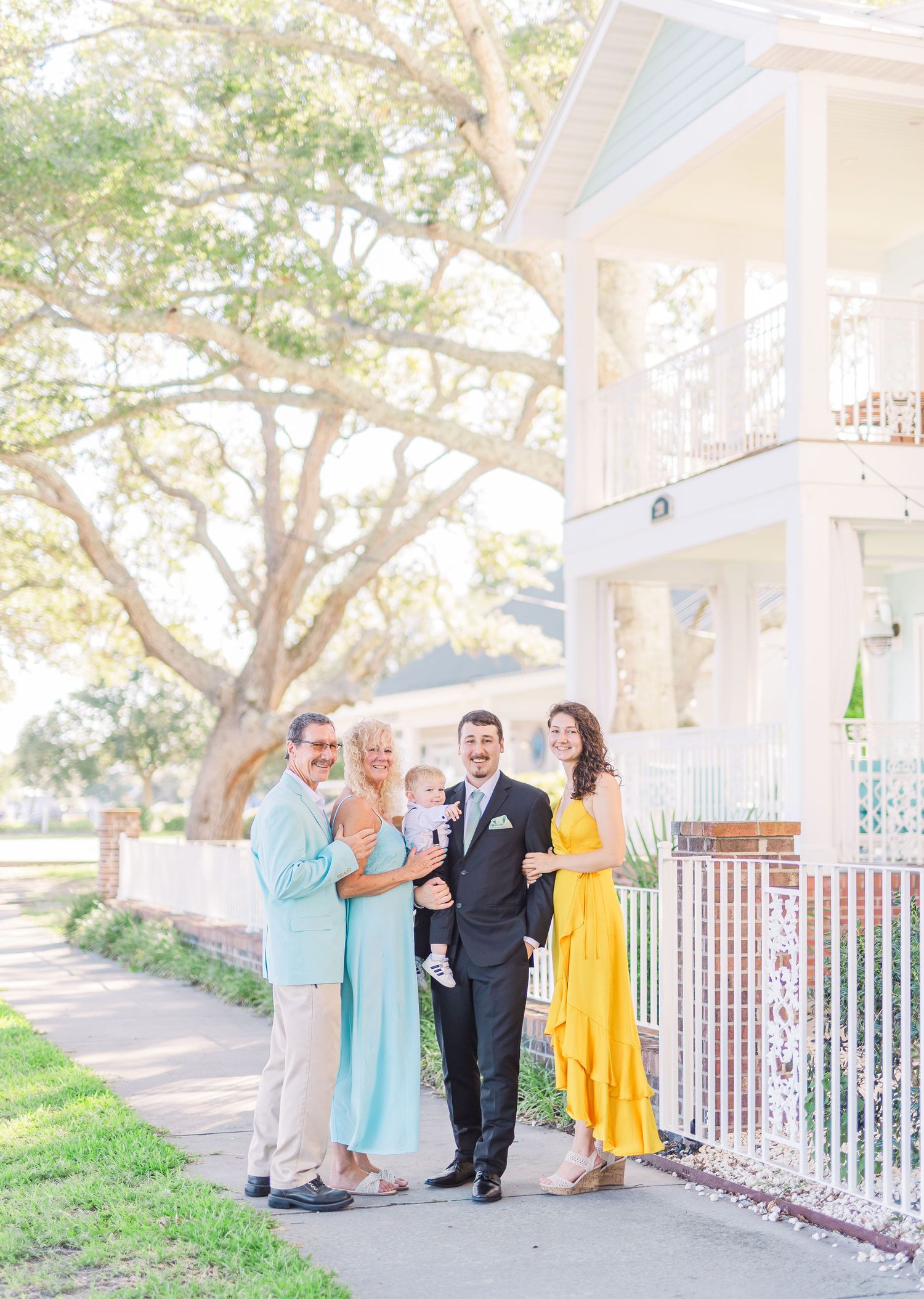 Wedding group photo session on a sunny porch with yellow and blue attire southport elopement wedding bride groom light and airy classic