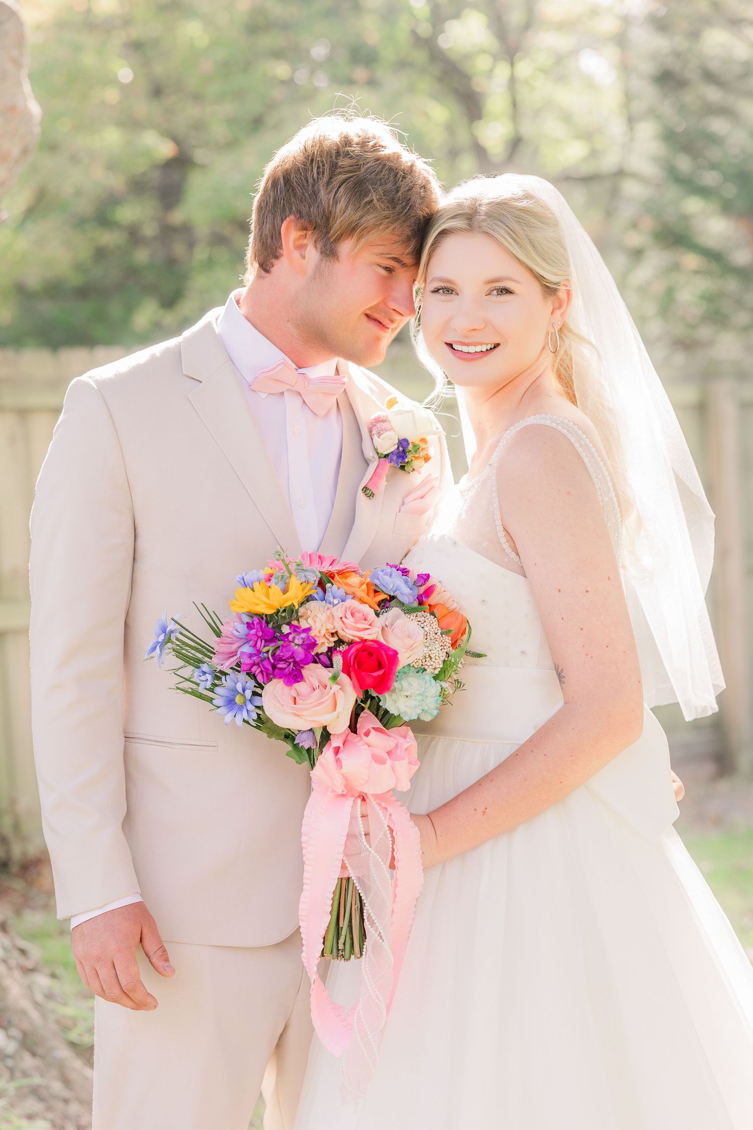 Newlyweds share tender moments while holding a colorful bouquet wedding groom bride wilmington photographer light and airy classic Wrightsvi