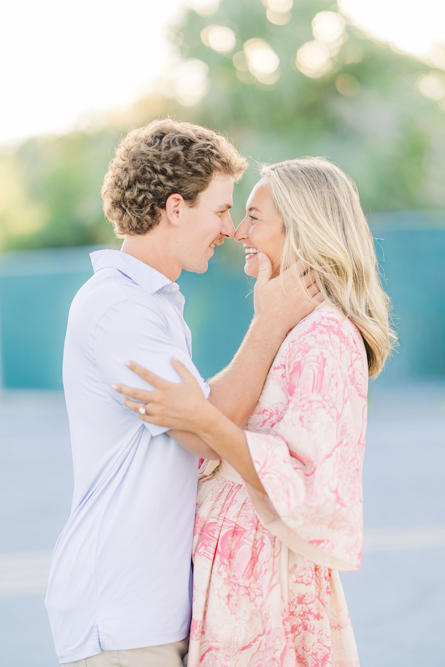 A tender moment between a couple in coordinating pink and white outfits against a blurred background.