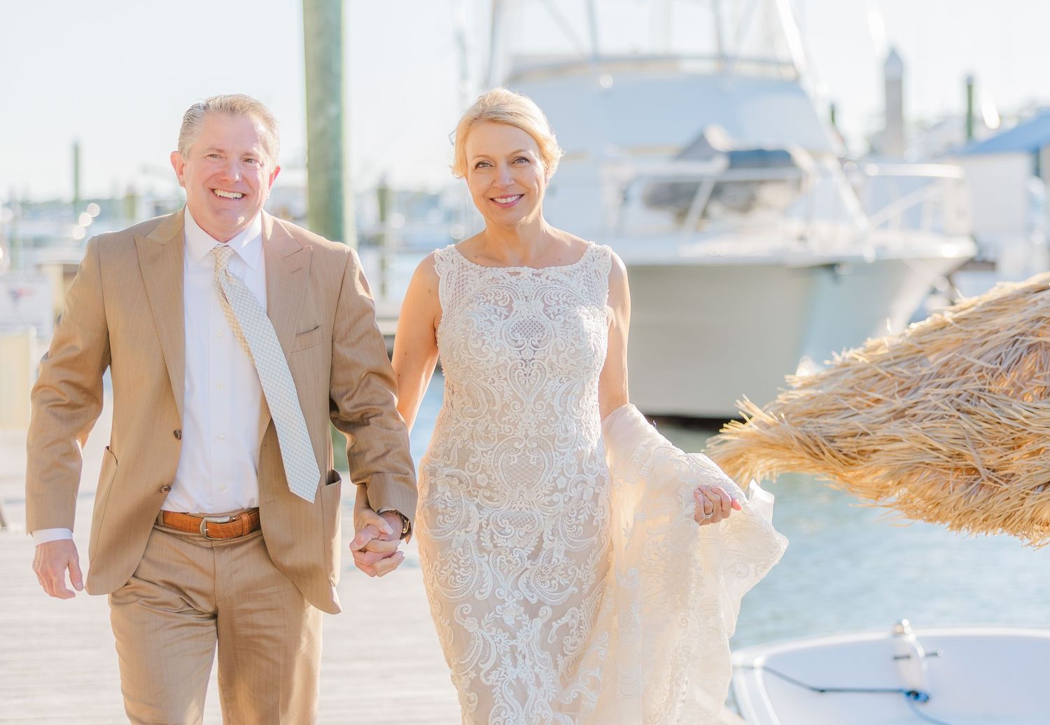 Elegant wedding party poses on a marina dock with boats in the background.