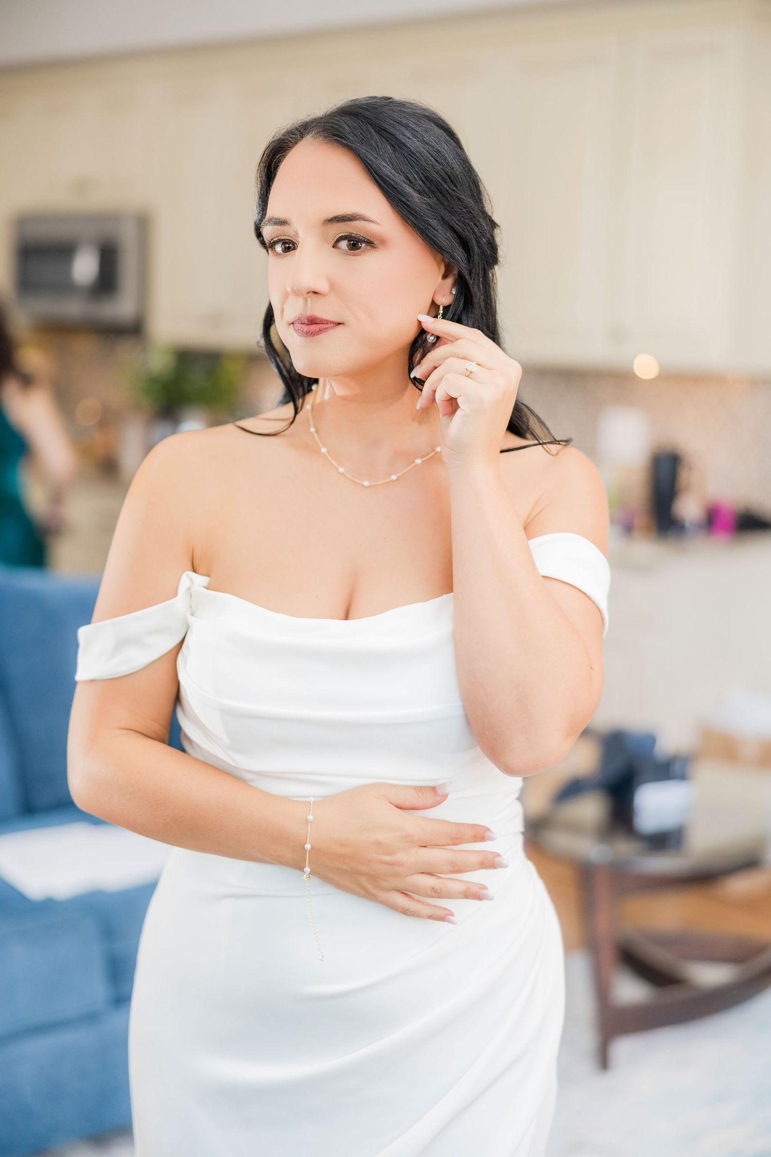 Elegant bride in off-shoulder white dress touching her earring while getting ready wedding groom bride lake Gaston photographer light airy