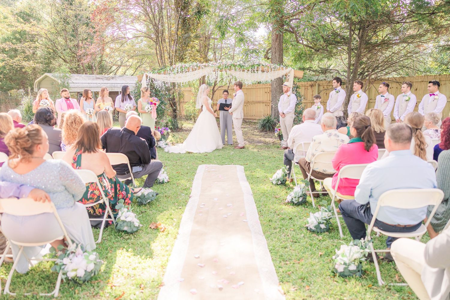 Panoramic view of an outdoor garden wedding ceremony with guests seated on white chairs wilmington bride groom light airy