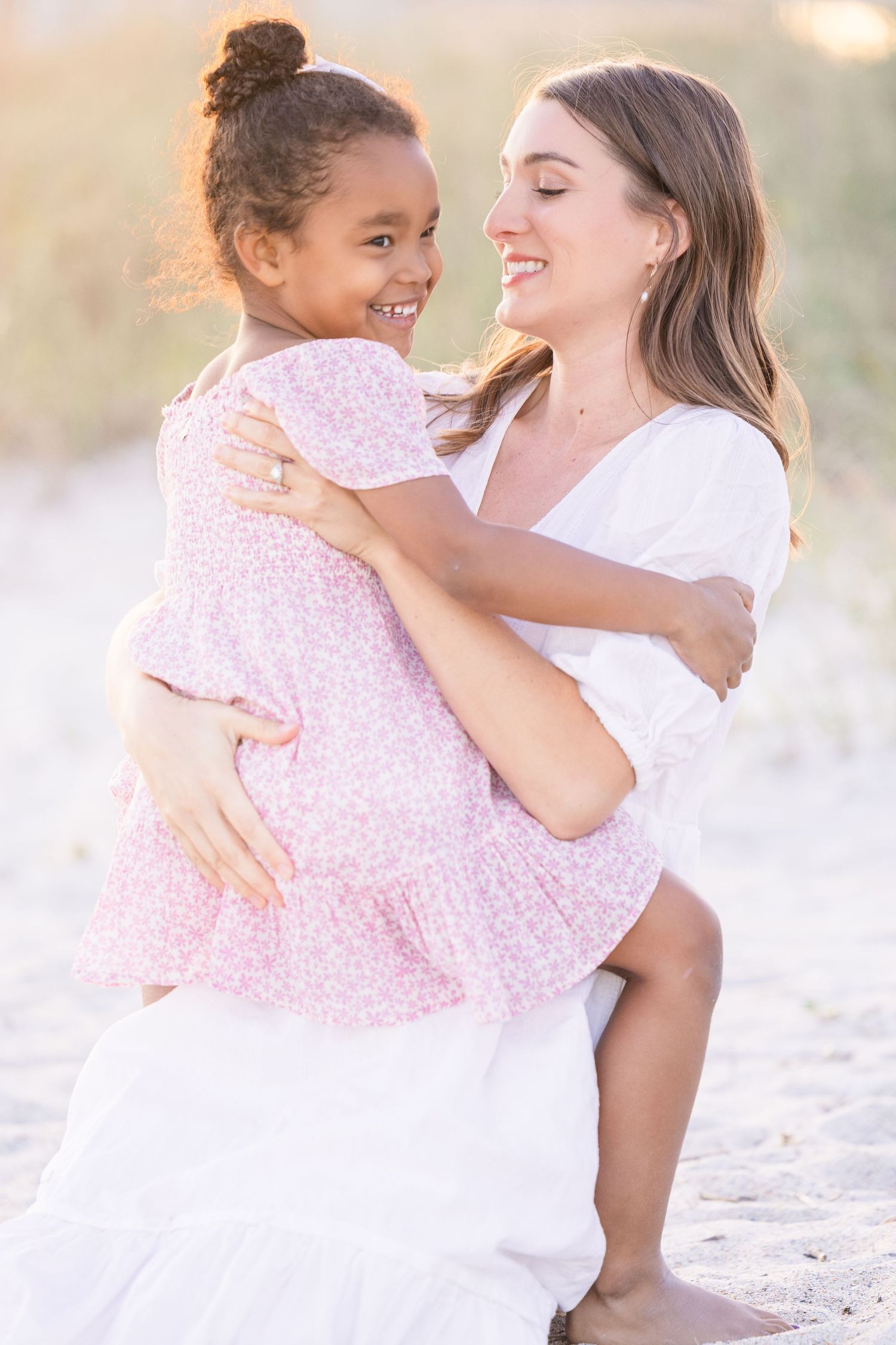 A tender moment between two people embracing and laughing against a sunset beach backdrop.