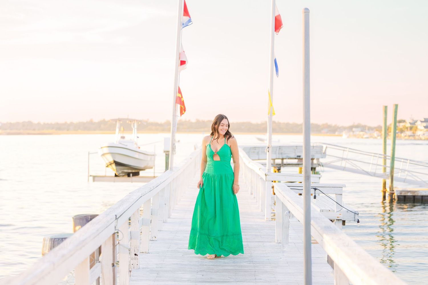 Waterfront dock scene with green dress against white railings and marina flags.