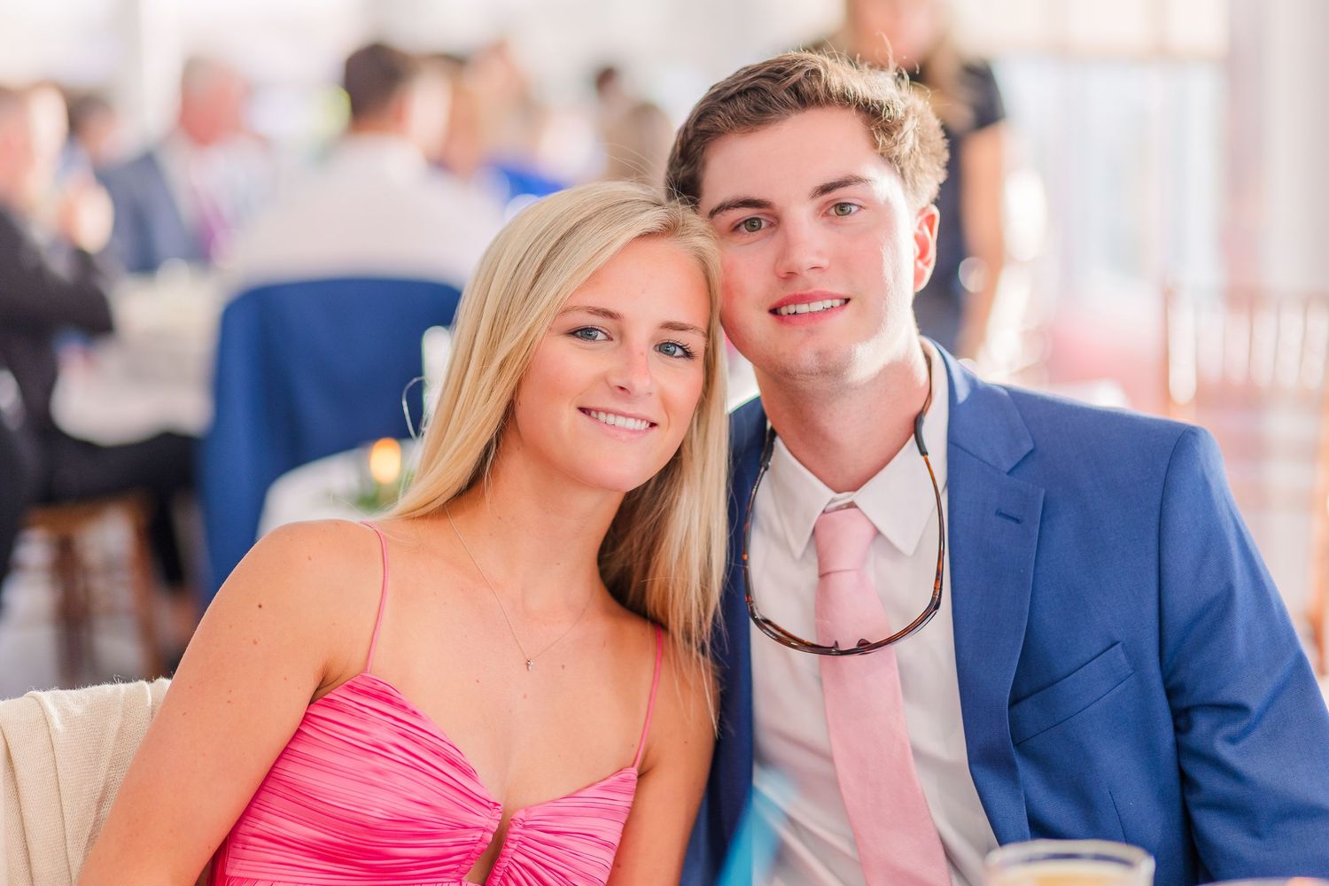 Wedding party in formal attire poses together on a sunny day with pink and blue color scheme.