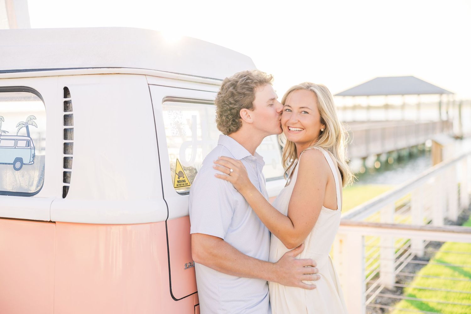 A sweet embrace captured against a retro pink and white van in warm sunlight.