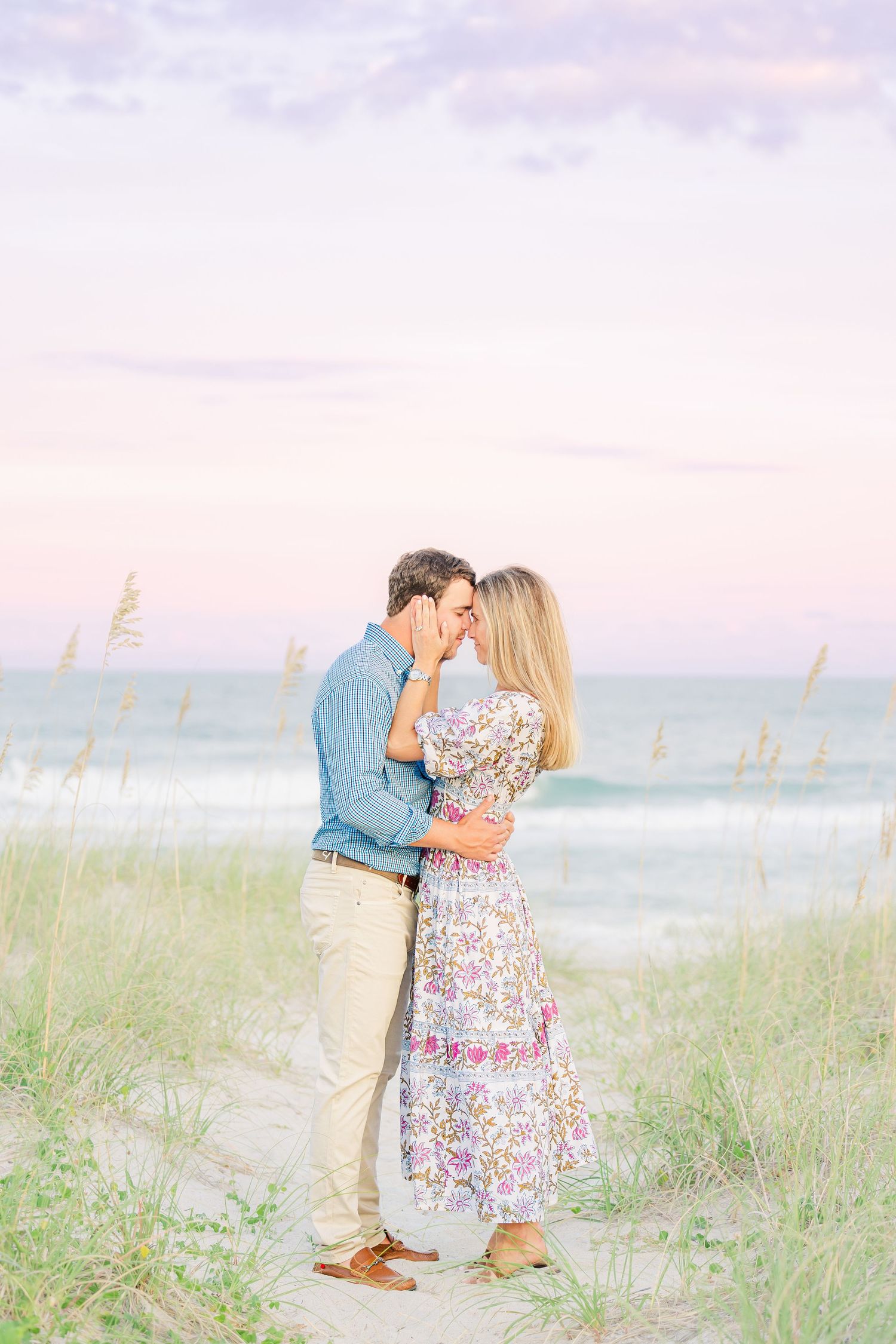 Couple sharing intimate moment on sandy beach path during sunset.