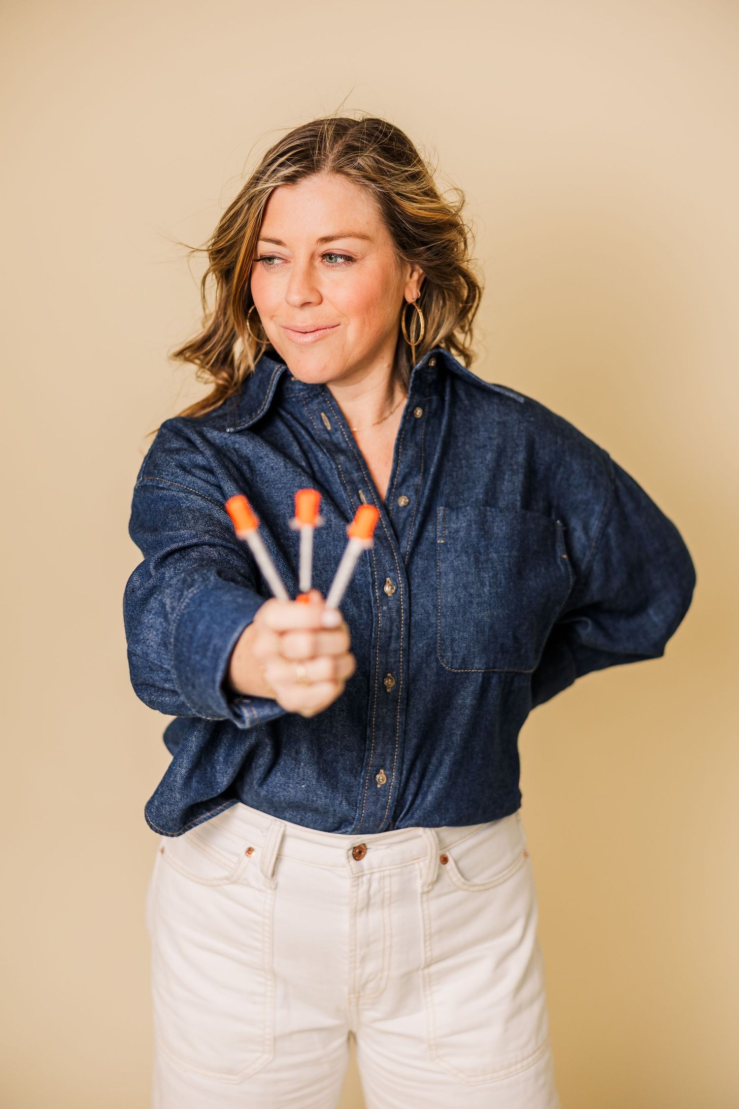 Playful fashion poses showing denim shirt and white pants against neutral background.