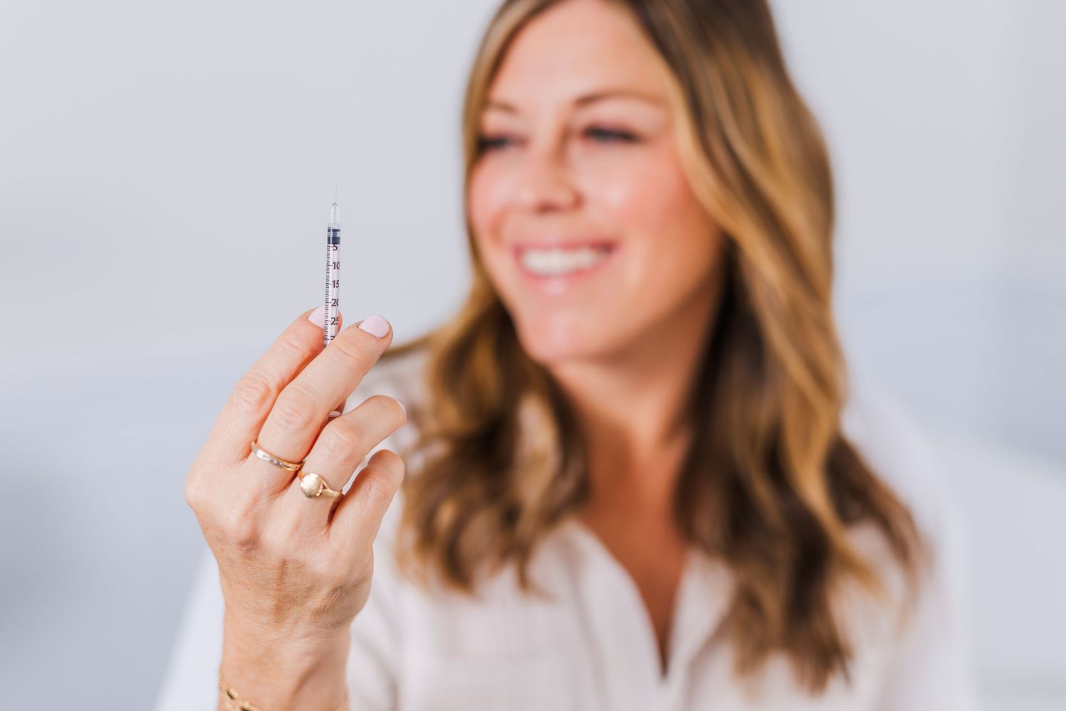 Close up shot showing hands holding a clear glass vial against light background.