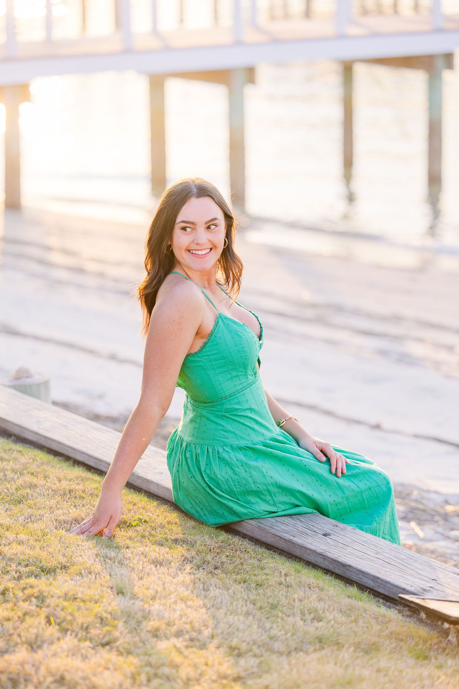 An emerald green sundress glows in warm evening light on a coastal boardwalk.