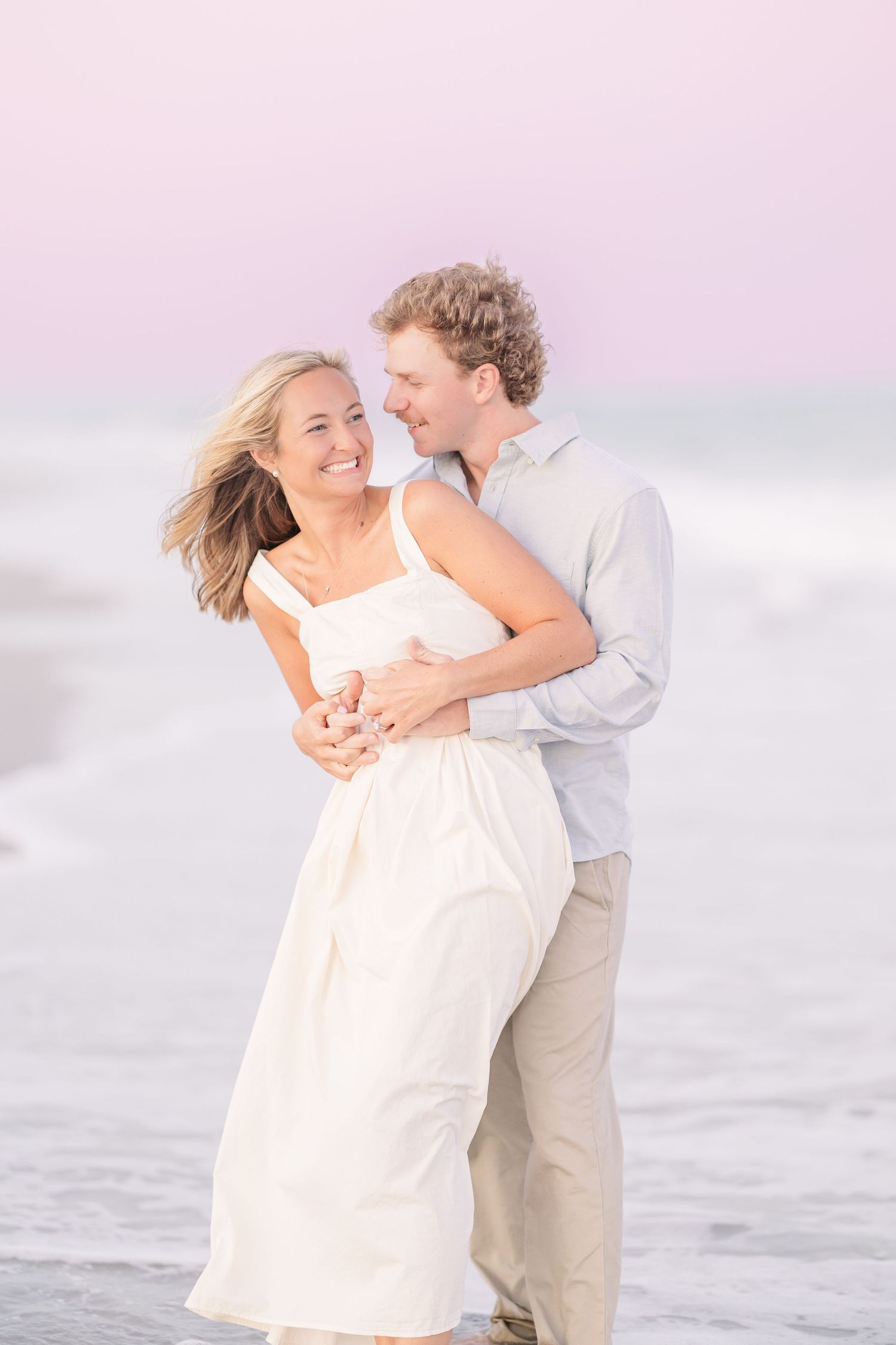 Couple shares intimate moment during beach photoshoot at sunset.