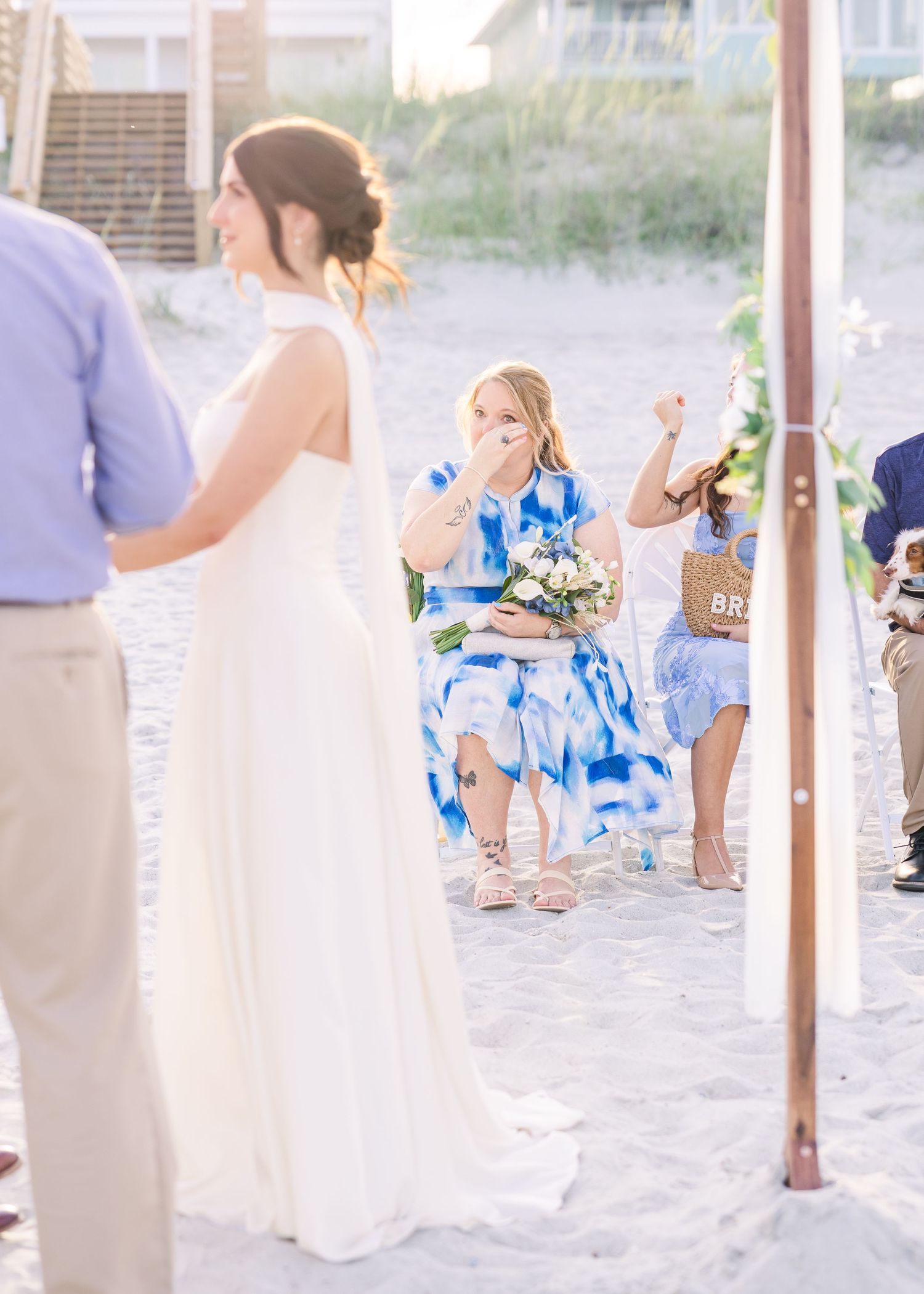 Emotional wedding guest in blue dress reacts during outdoor beach ceremony at sunset in Carolina Beach near Wilmington, NC.