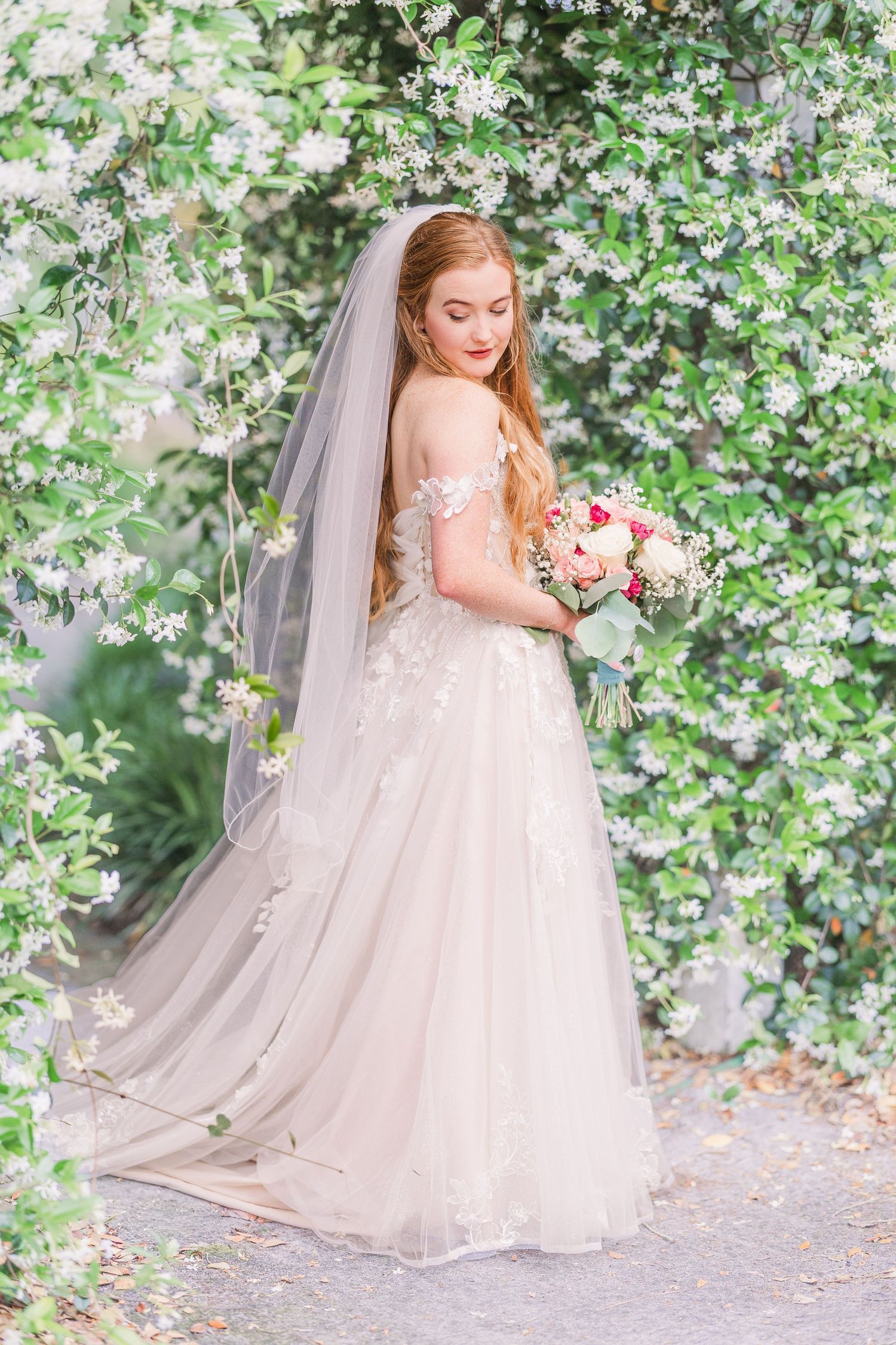 Ethereal bridal portraits showcasing flowing tulle gown against backdrop of delicate white flowers in harborway gardens in Wrightsville Beac