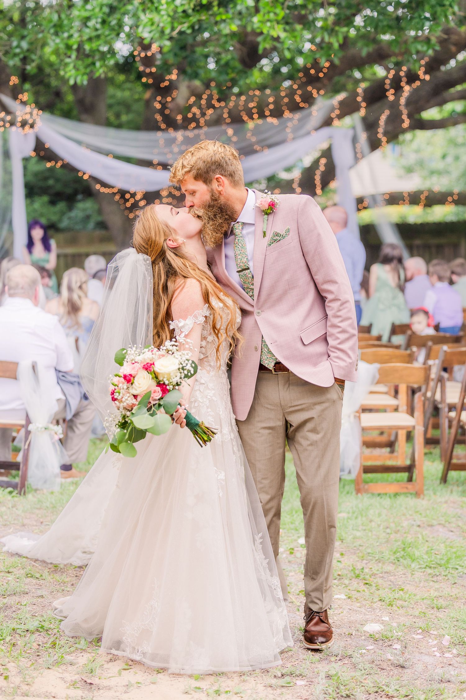 Romantic wedding portrait under string lights and draped fabric in an outdoor garden setting in harborway gardens in Wrightsville Beach, nc