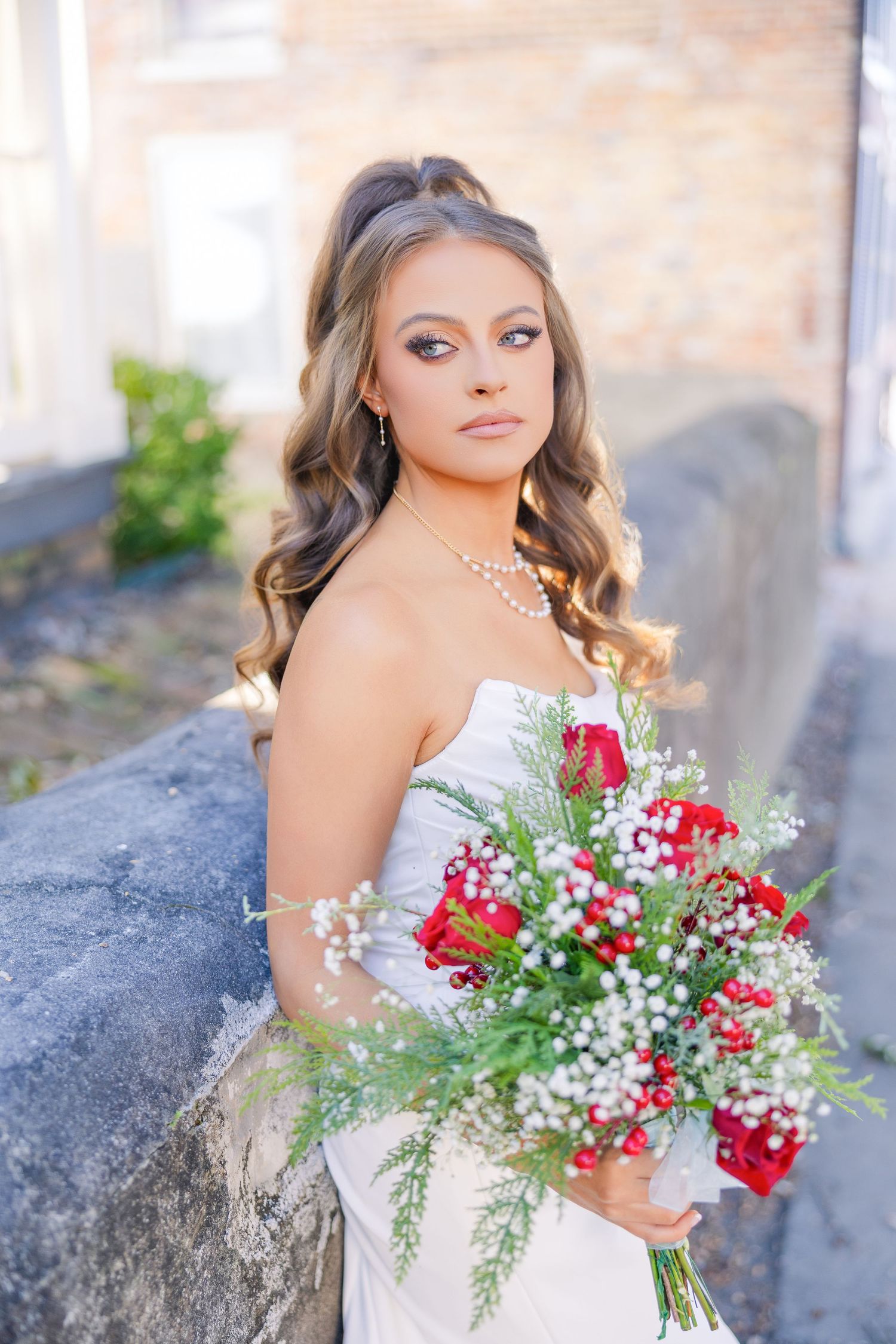 Artistic bridal photos with red and white bouquet against stone backdrop.