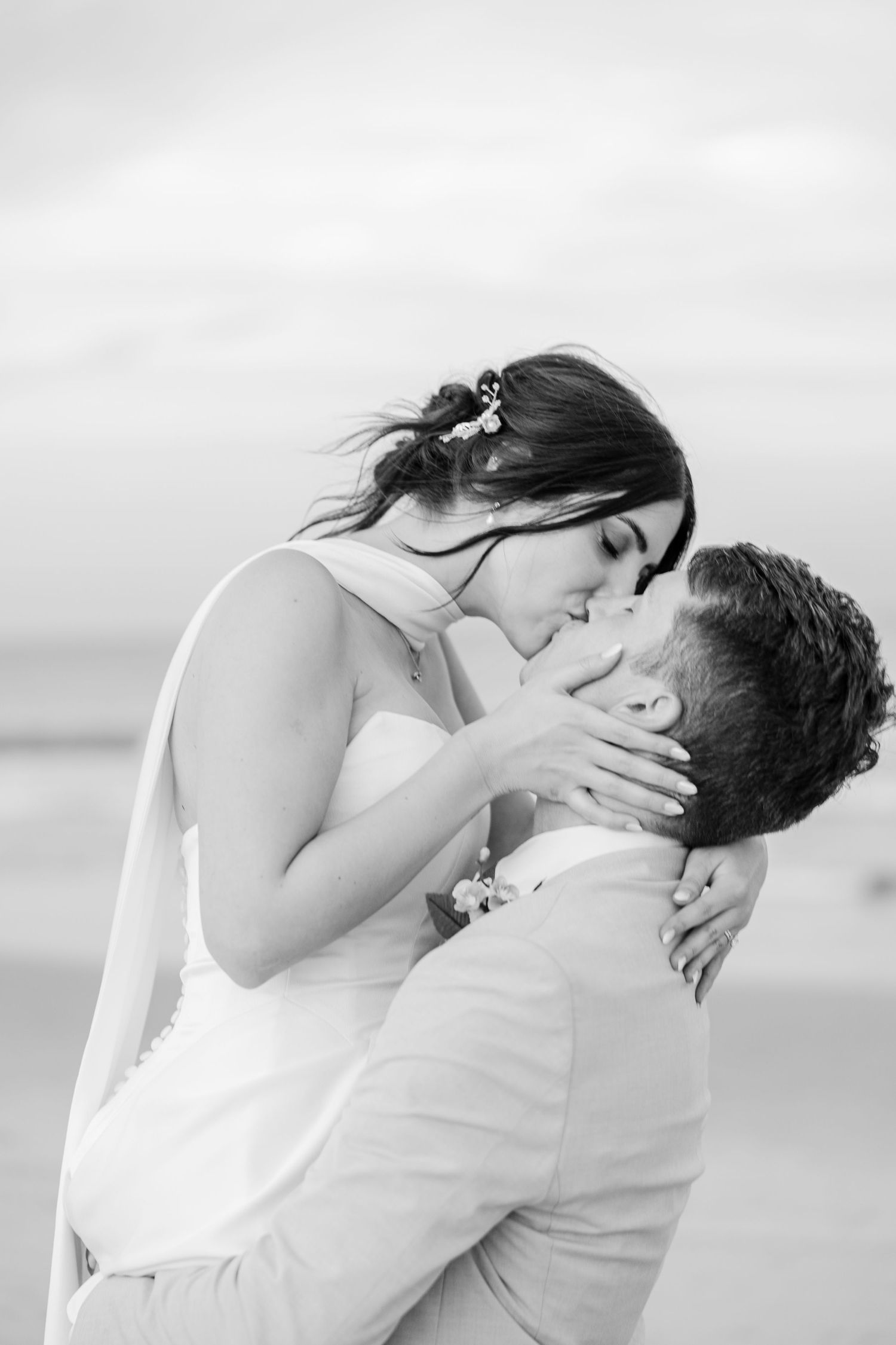 Black and white romantic photo of bride and groom sharing a passionate kiss on the beach in Carolina Beach near Wilmington, NC.