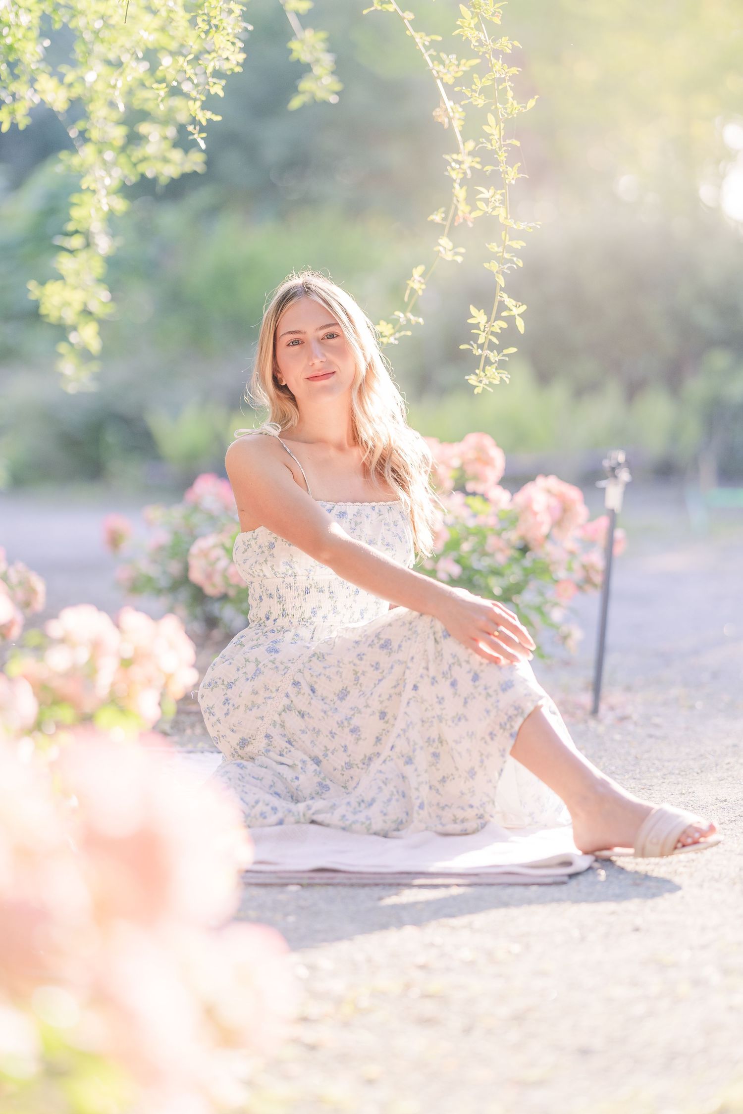 Romantic garden scene with someone relaxing on the ground in a flowing white dress.