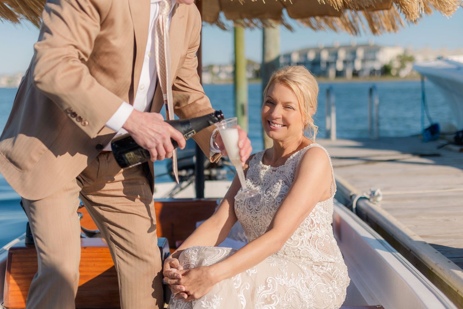 A waterfront celebration with people in formal attire on a wooden dock.