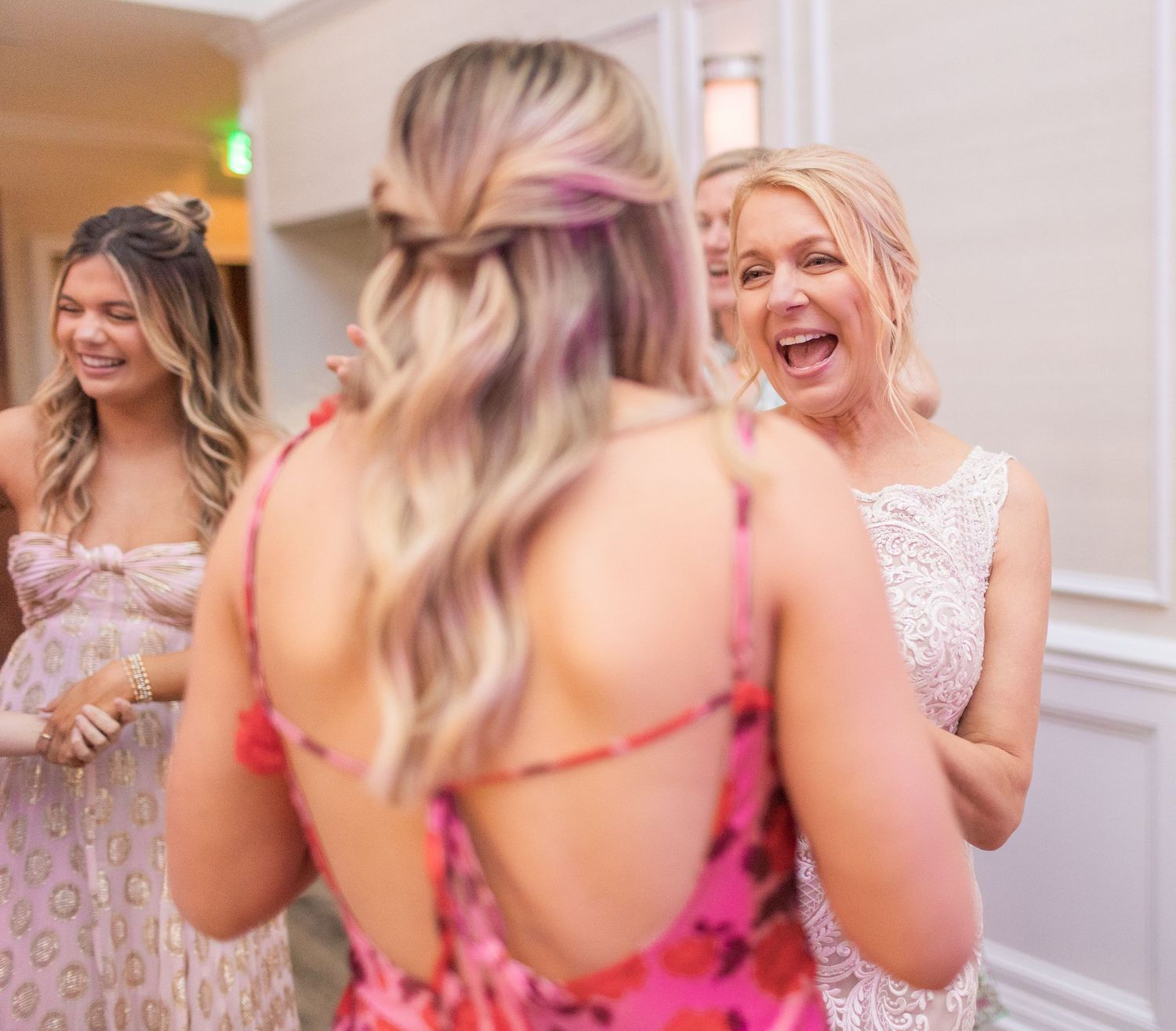 Wedding guests share joyful laughter during a celebration in an elegant indoor venue.