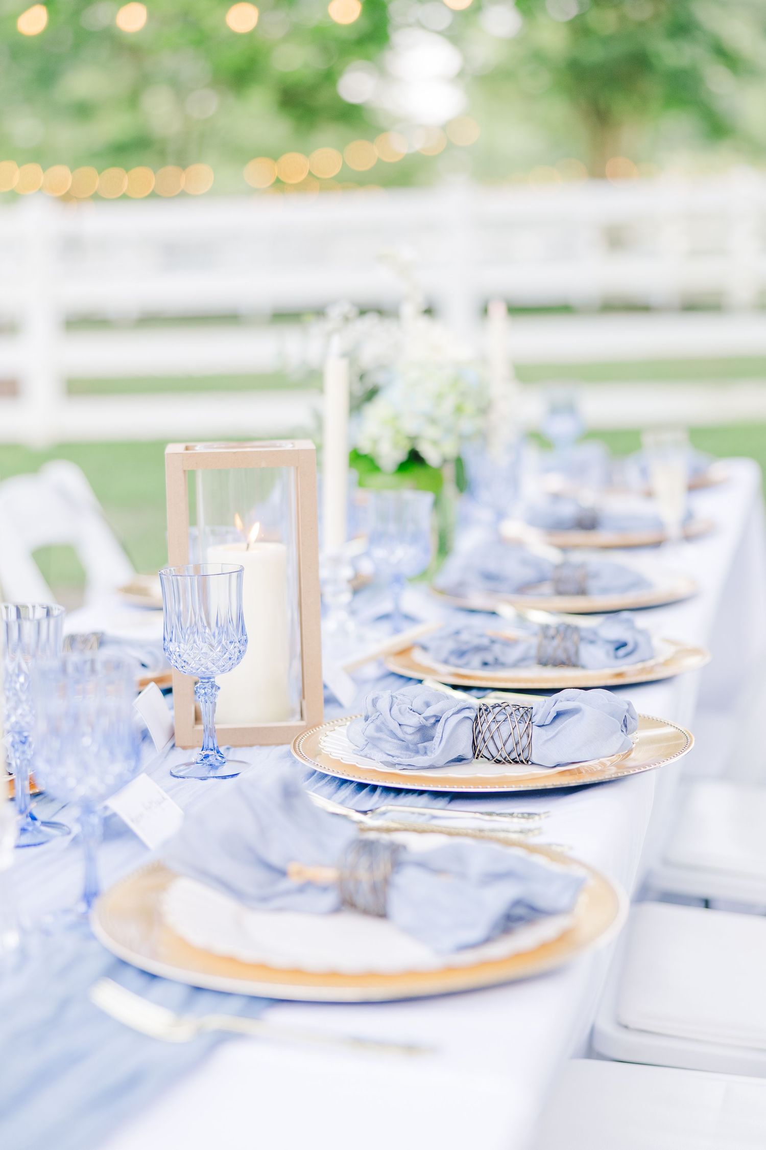 Elegant table with light blue linens and gold charger plates arranged for a wedding dining event at sycamore bend estate in wilmington, NC