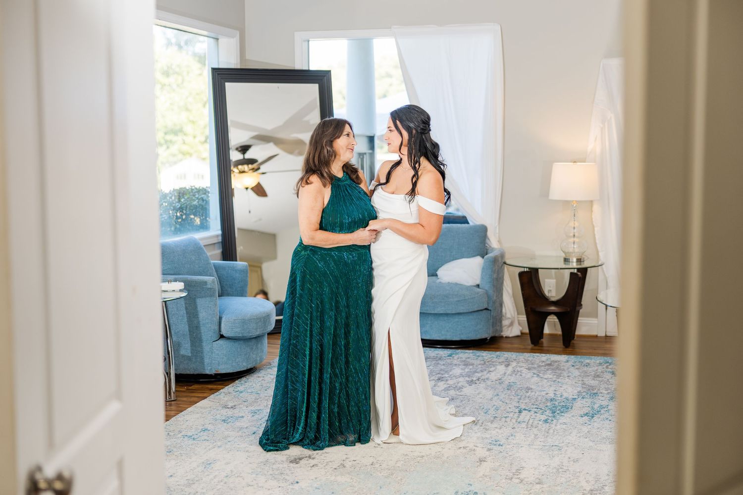 Two women share a moment in a bright room with blue furniture and modern decor wedding groom bride lake Gaston photographer light airy