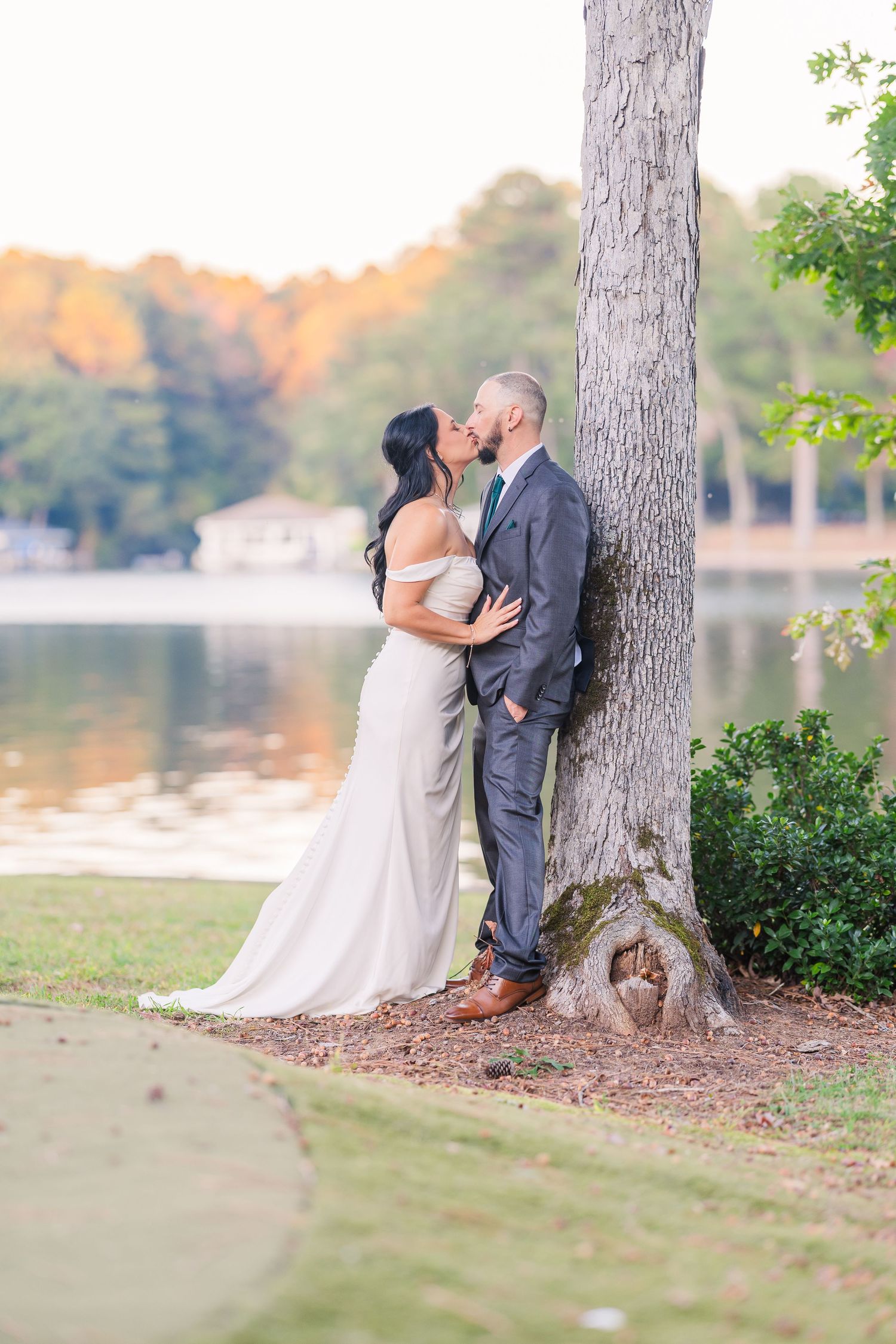 Romantic wedding portraits taken against large tree trunks near a peaceful lake wedding groom bride lake Gaston photographer light airy