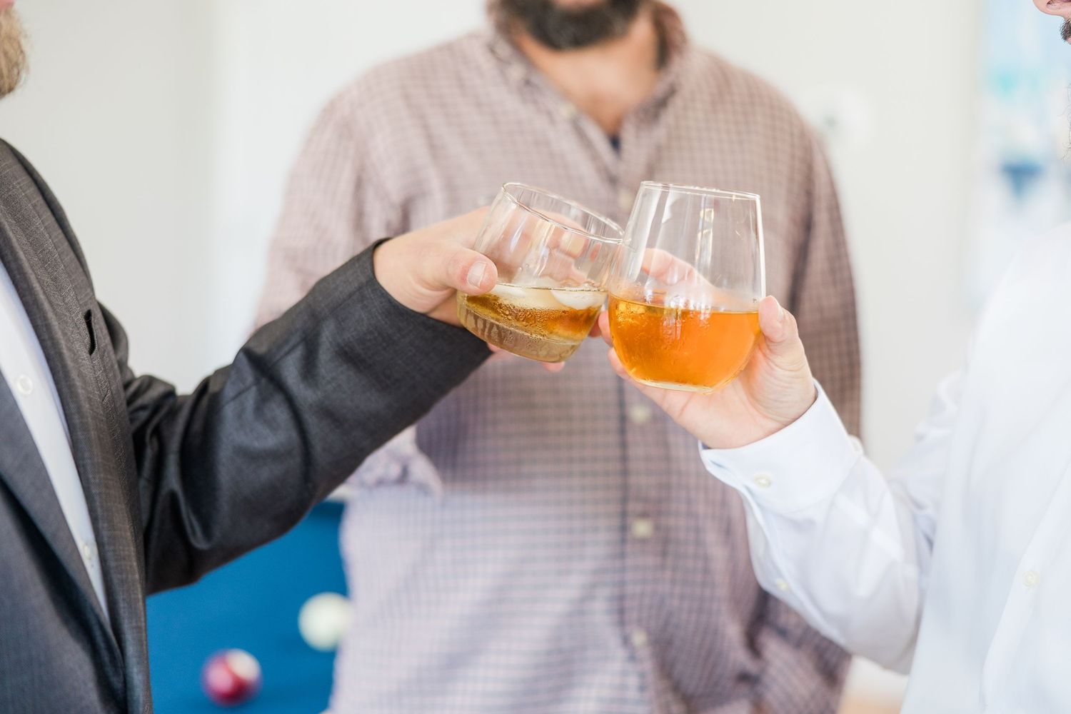 Three people in business attire share drinks and conversation at a casual gathering wedding groom bride lake Gaston photographer light airy