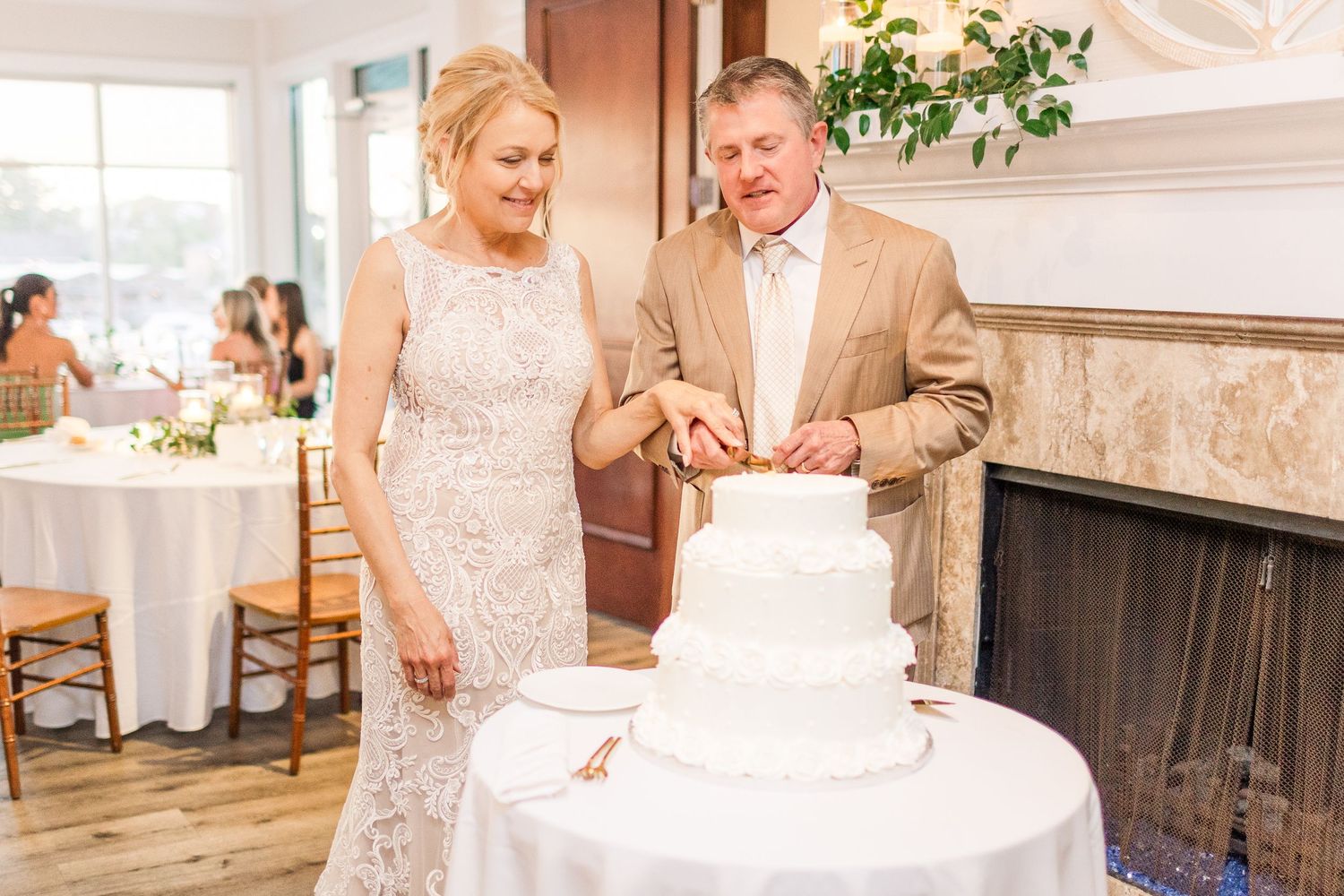 Wedding cake cutting ceremony in an elegant indoor venue with white decor.