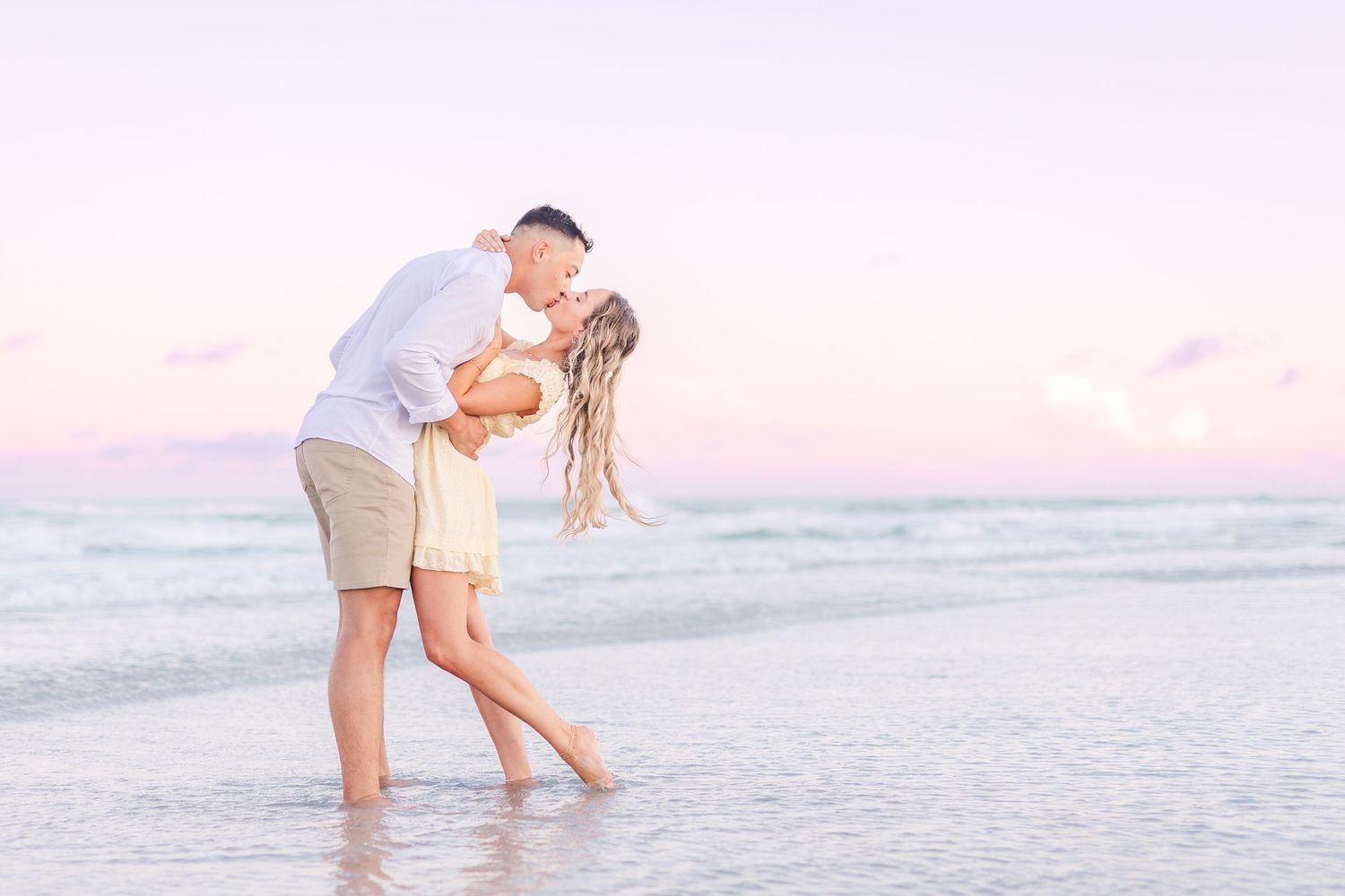 Romantic couple embracing at sunset on a peaceful beach with soft pink sky Wrightsville Beach wedding classic light and airy