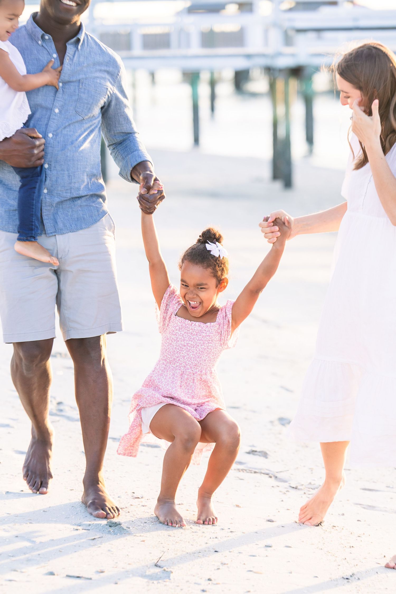 Family playing together on sandy beach during golden hour photoshoot.