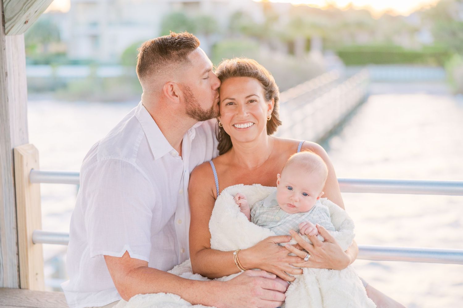 Family shares intimate moments on wooden deck during golden hour photoshoot.