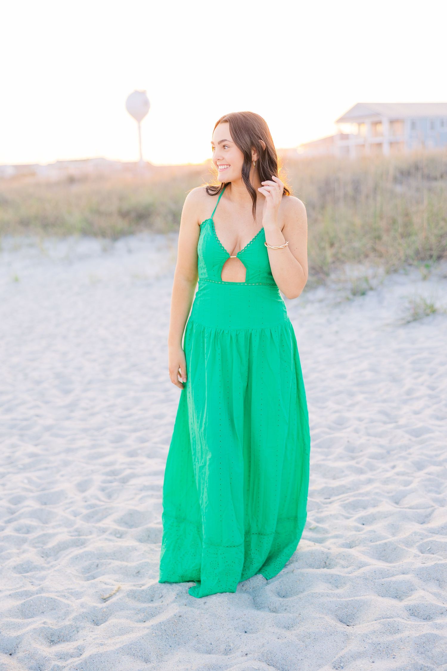 Casual beach portraits with a bright green summer dress against white sand.