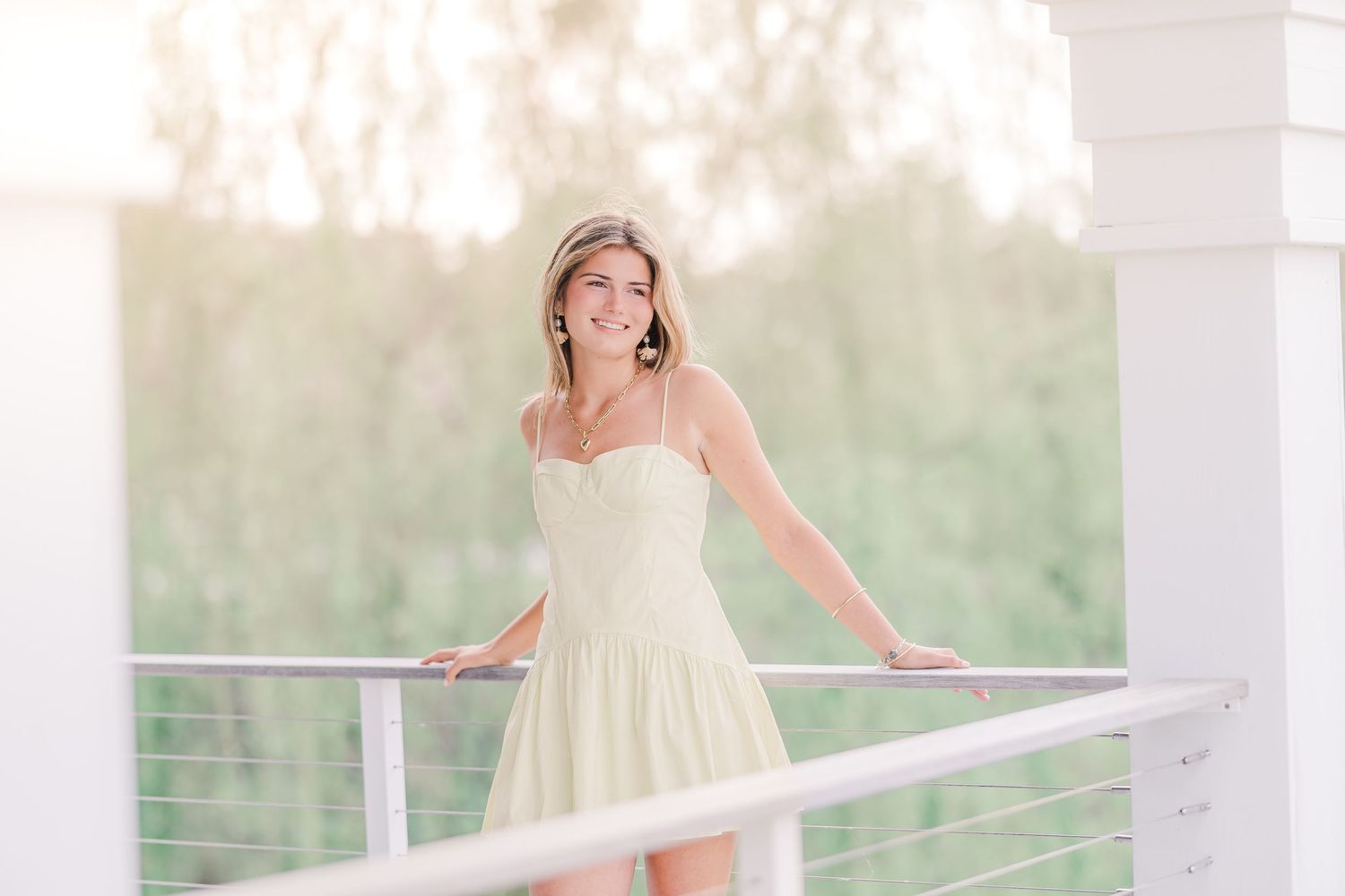 Ethereal outdoor photoshoot on a white deck with natural backlighting and cable railings.