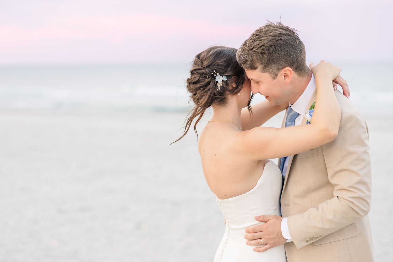 Bride and groom share a tender forehead touch embrace on the beach at sunset after wedding in Carolina Beach near Wilmington, NC.