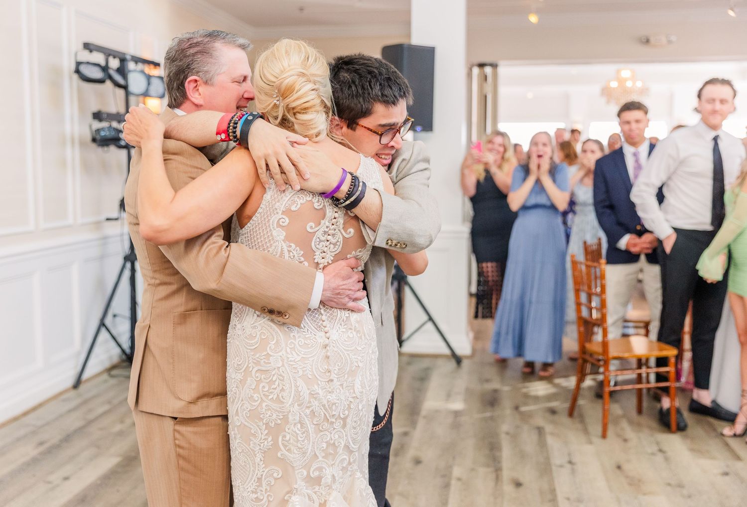 Wedding reception dance floor with guests in formal wear sharing heartfelt moments.