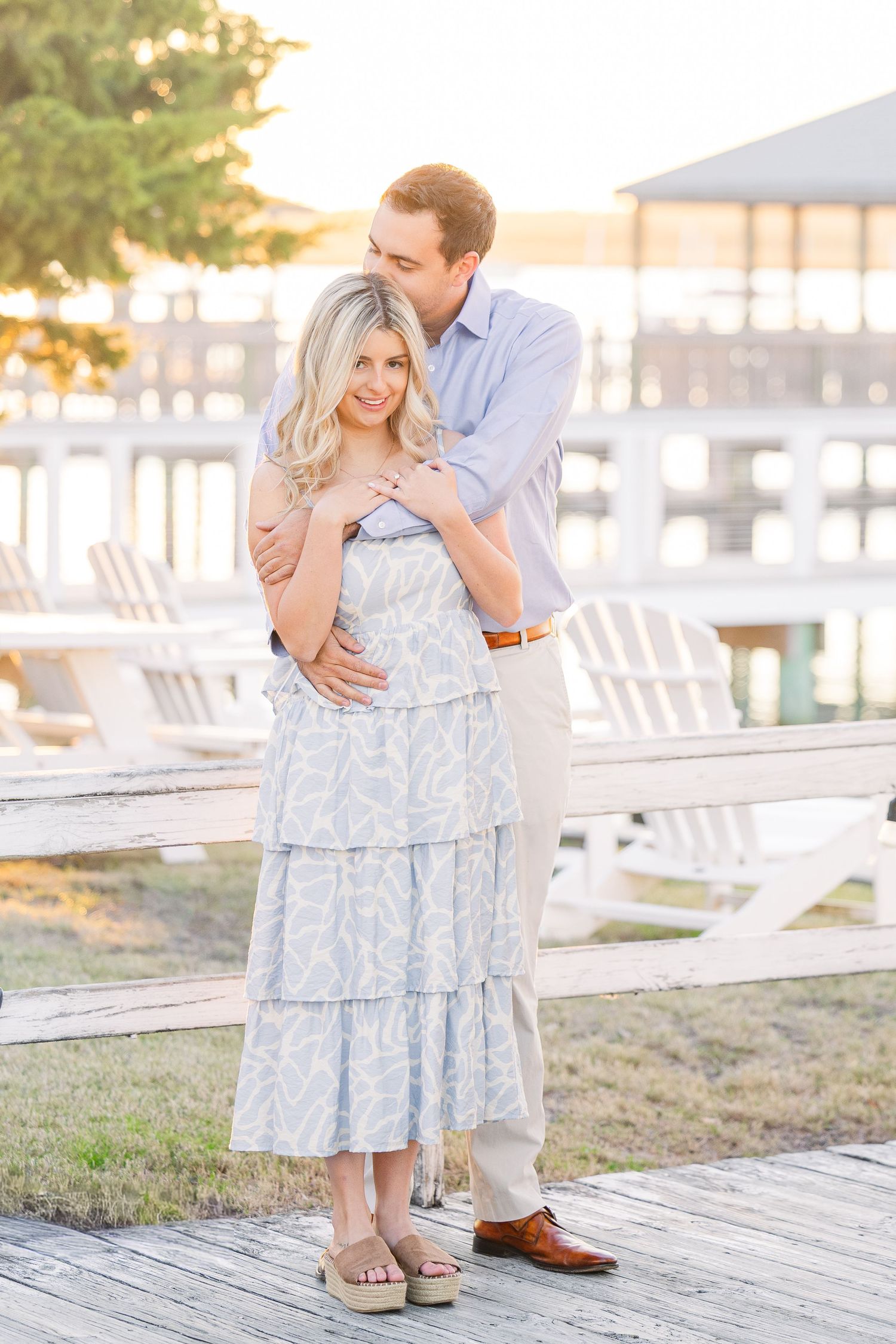 Intimate moment captured on waterfront deck during sunset with soft golden lighting.