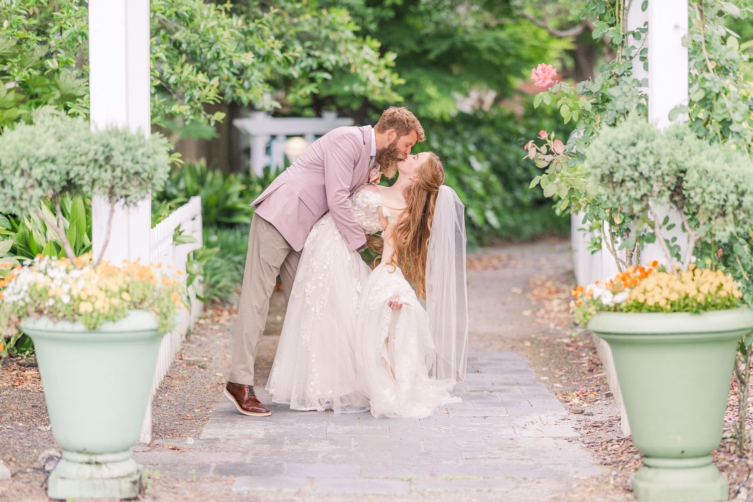 Wedding couple photographed along garden path with decorative planters and greenery in harborway gardens in Wrightsville Beach, nc