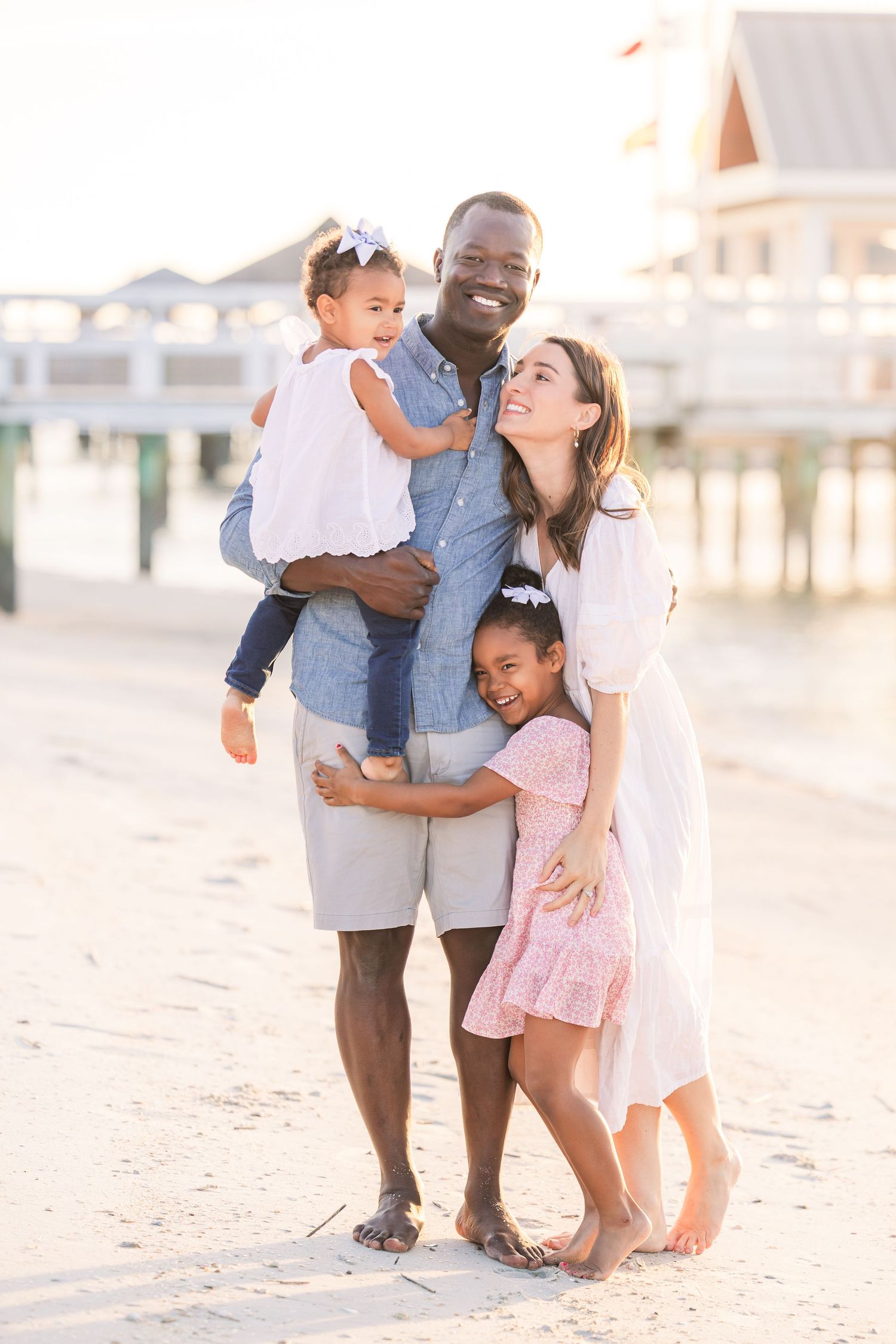 Family portrait session on beach with soft sunset lighting.