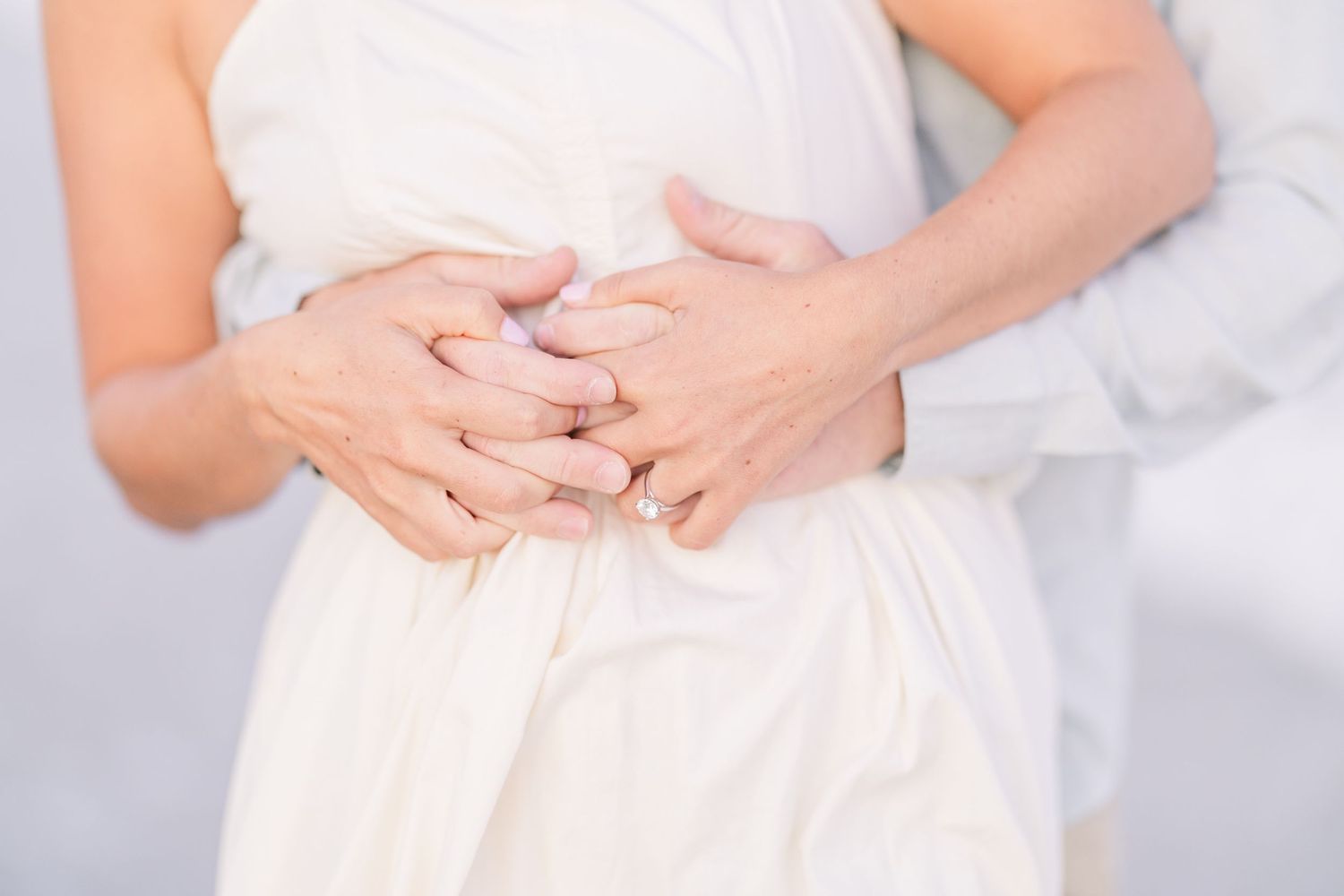 Close-up of hands with rings during romantic beach photoshoot.