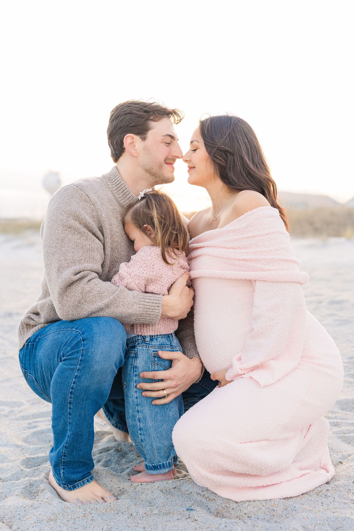 Intimate family moments captured while sitting on beach sand during sunset.