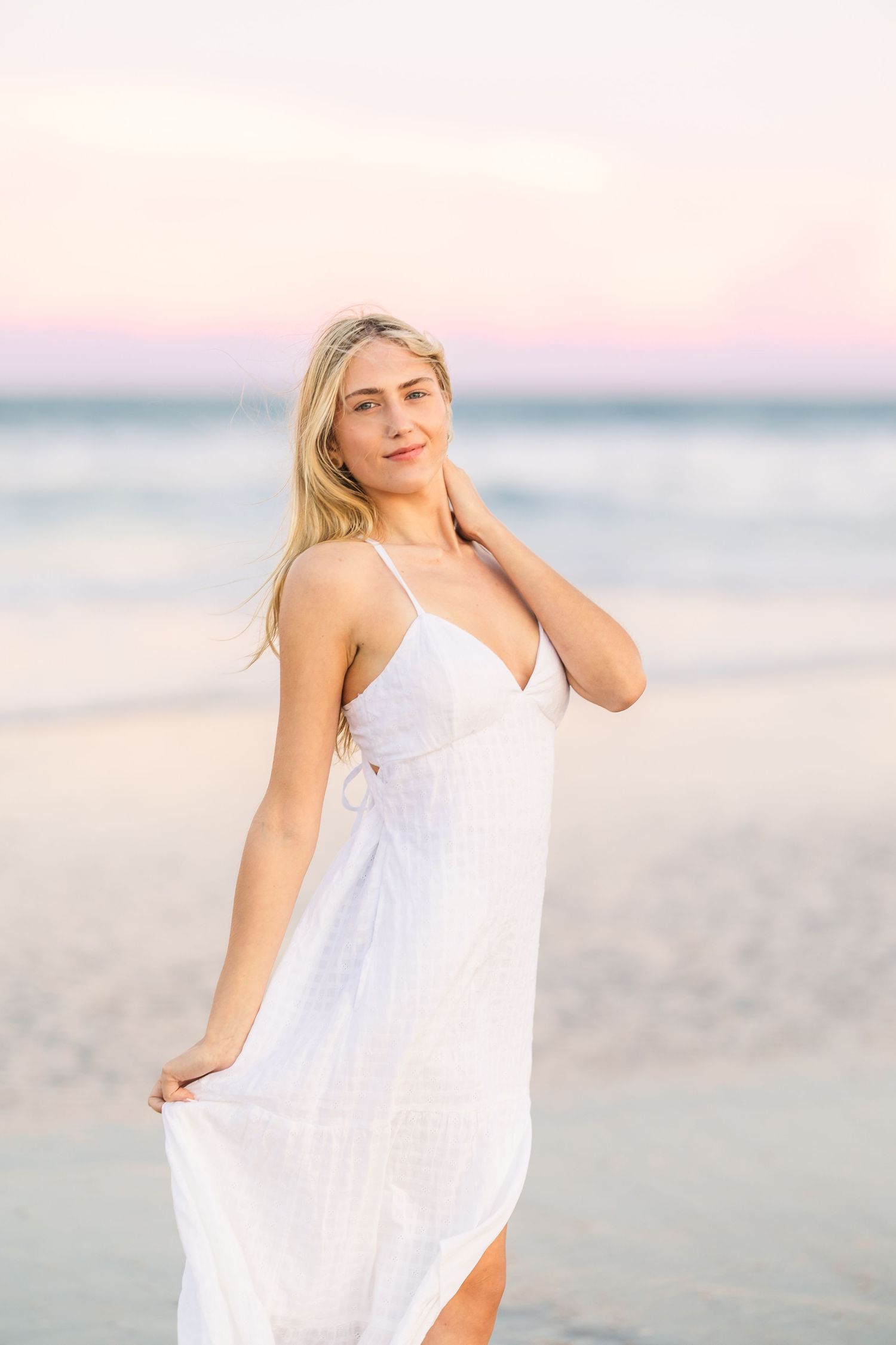 Ethereal beach photoshoot featuring model in white sundress at dusk.