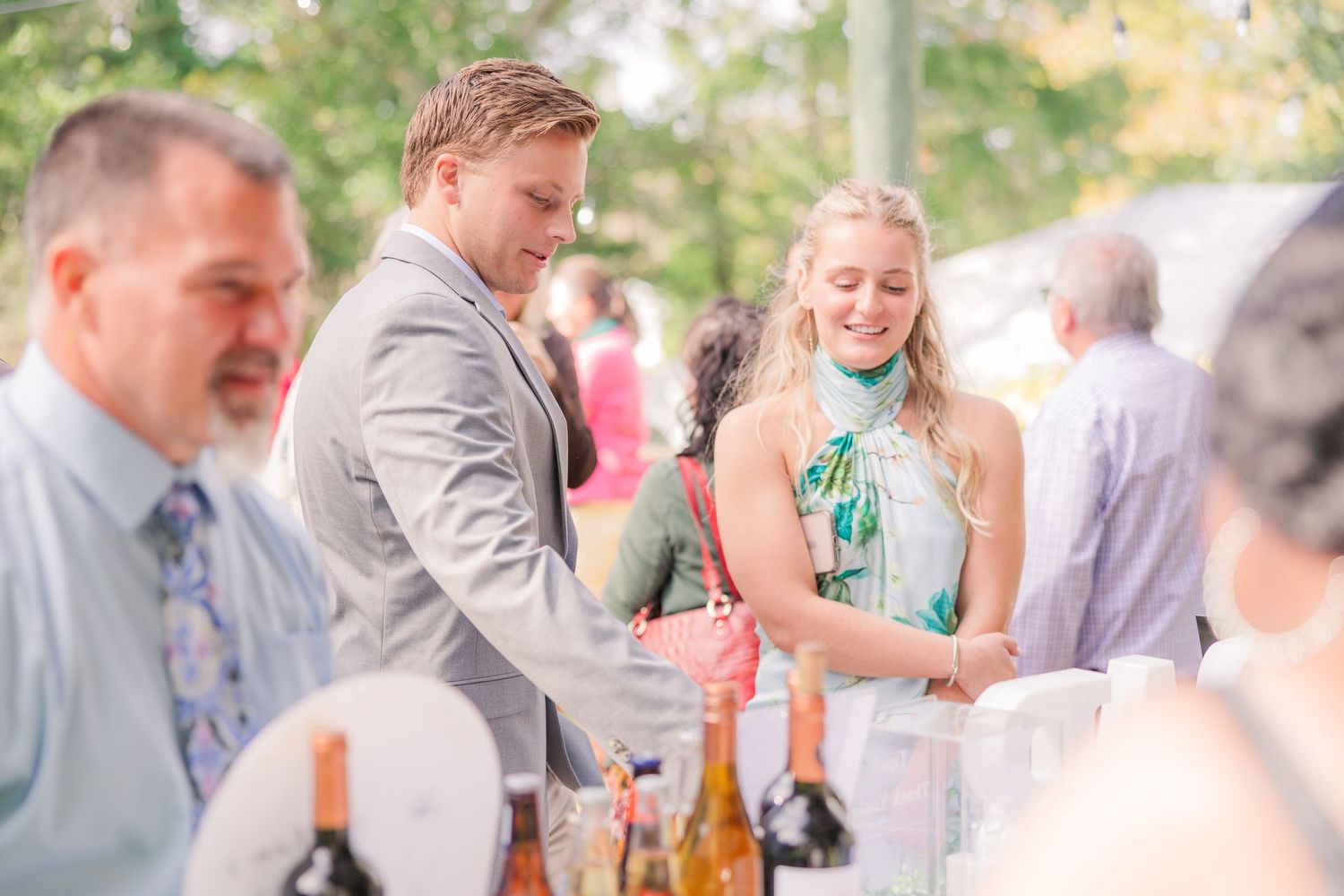 Wedding guests mingle and celebrate at an outdoor reception with drinks and laughter.