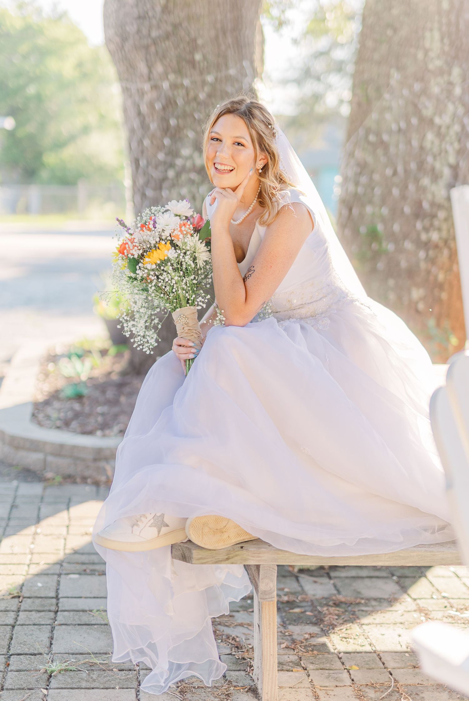 Bride in flowing white gown poses on stone bench under oak trees southport elopement wedding bride groom light and airy classic