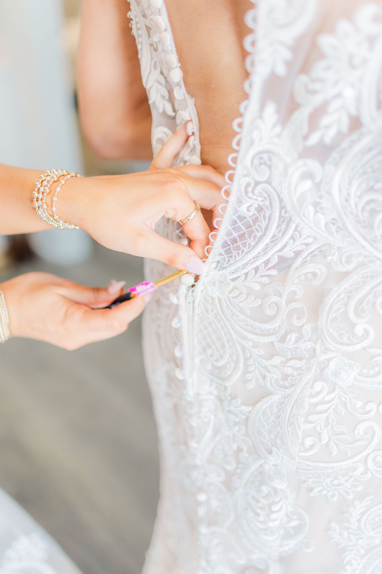 Close-up details of intricate white lace wedding dress with delicate buttons.