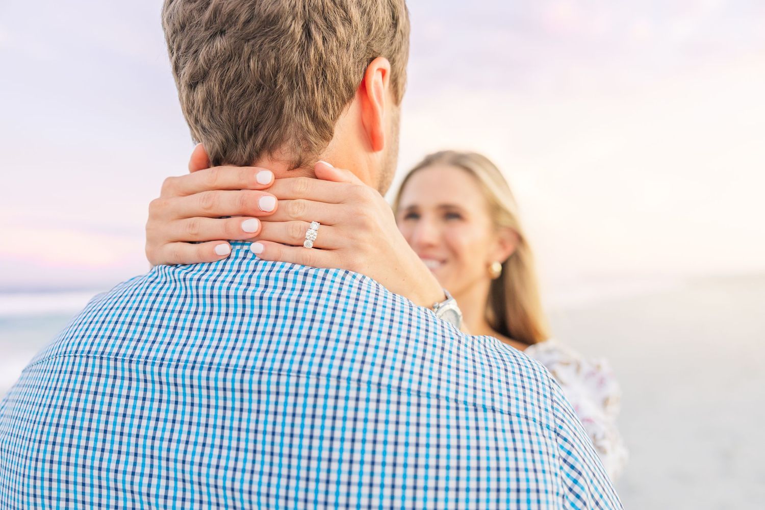 Close-up view of couple embracing with ocean backdrop at dusk.