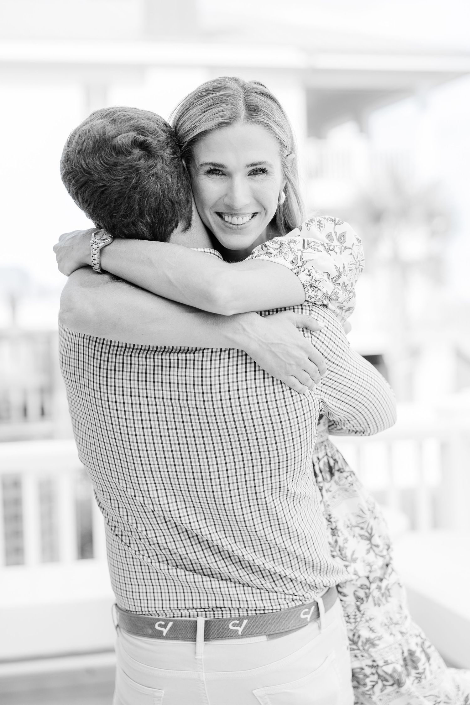 Black and white portrait of a joyful embrace on a sunny porch.